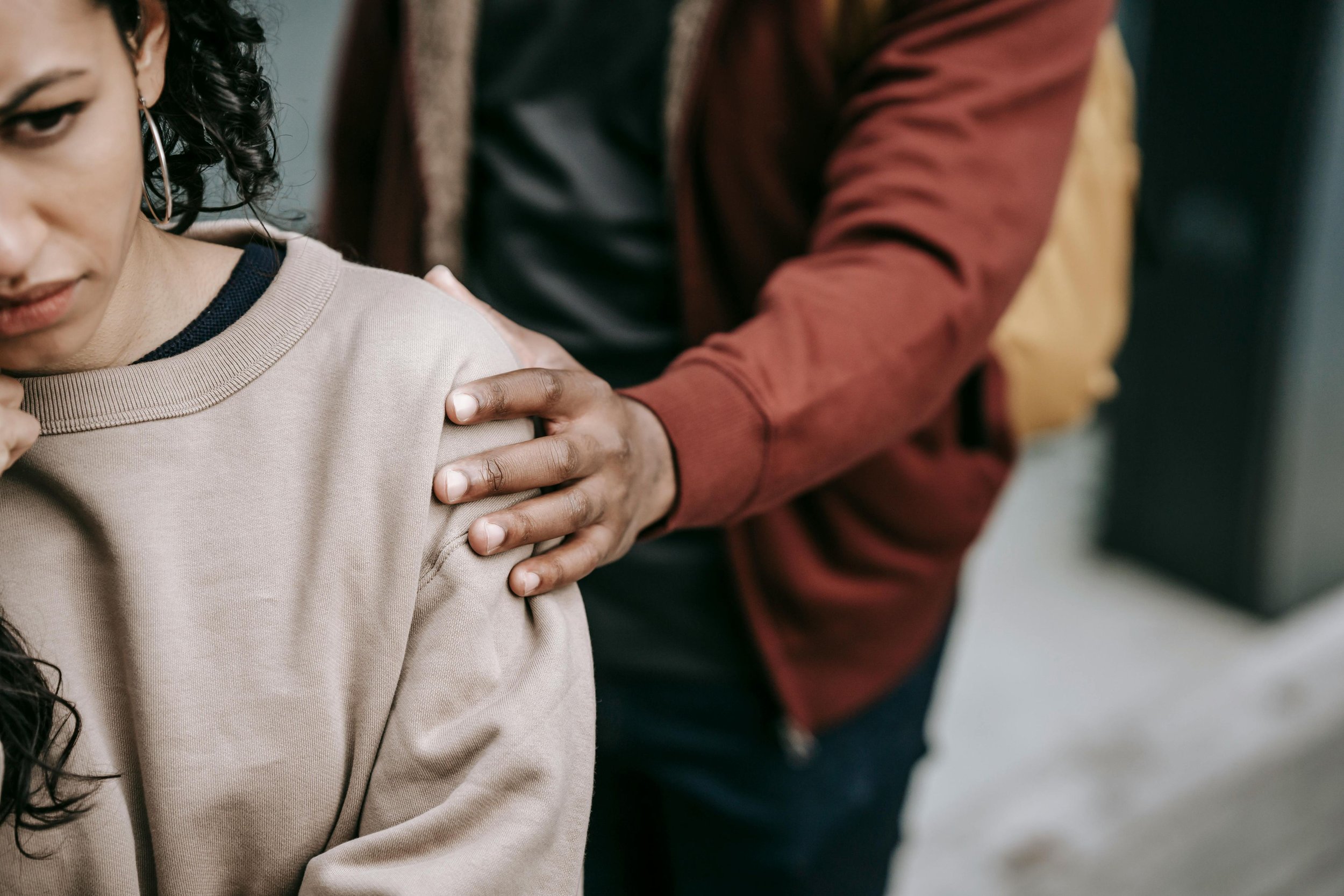A close-up of a woman receiving a vaccination shot on her upper arm from a healthcare worker, with the woman's face partially visible and the healthcare worker's hand and arm in focus.