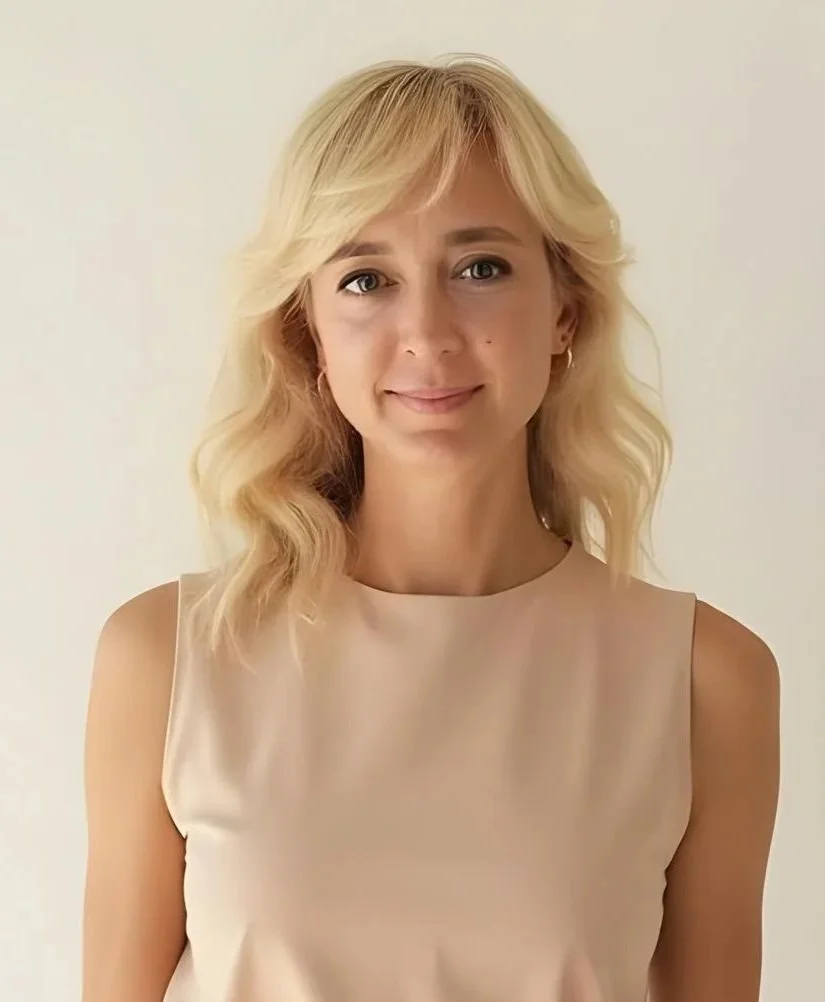 Smiling woman with blonde hair in a sleeveless pink top.