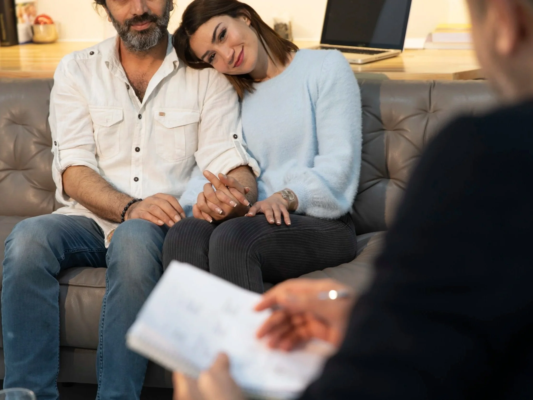 A woman and a man holding hands with each other during a counseling session with a therapist.