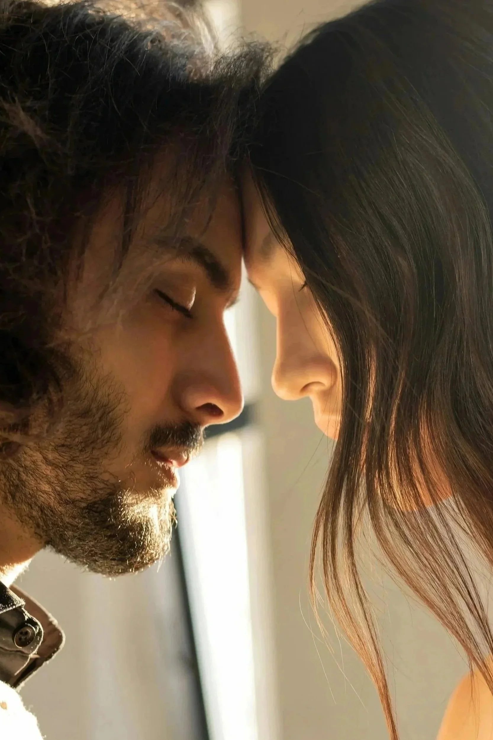 A close-up of a man and woman with foreheads touching, eyes closed, sharing an intimate moment.