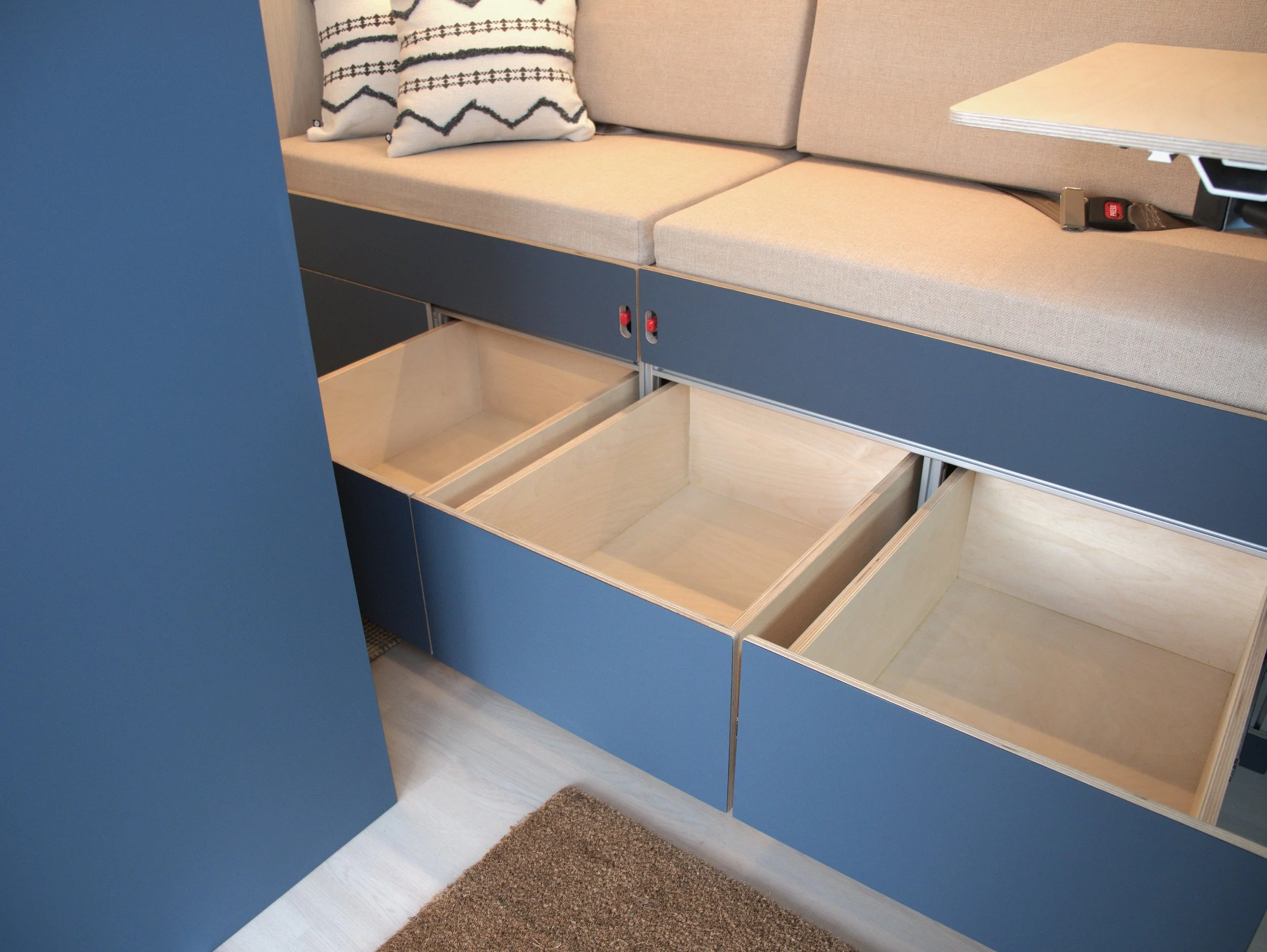 Under-bench storage drawers in 'Nordlys' — three blue-faced drawers simultaneously extended beneath the bench seat, showing the built-in storage capacity