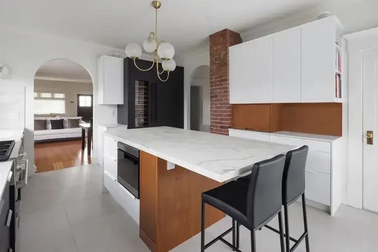 A modern kitchen featuring white cabinets and a sleek marble countertop, showcasing a clean and elegant design.