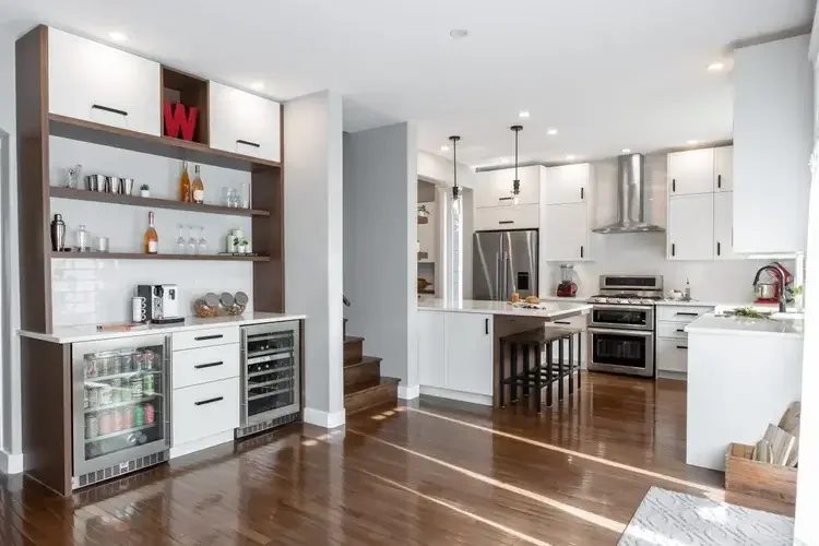 A modern kitchen featuring white cabinets and warm wood flooring, creating a bright and inviting atmosphere.
