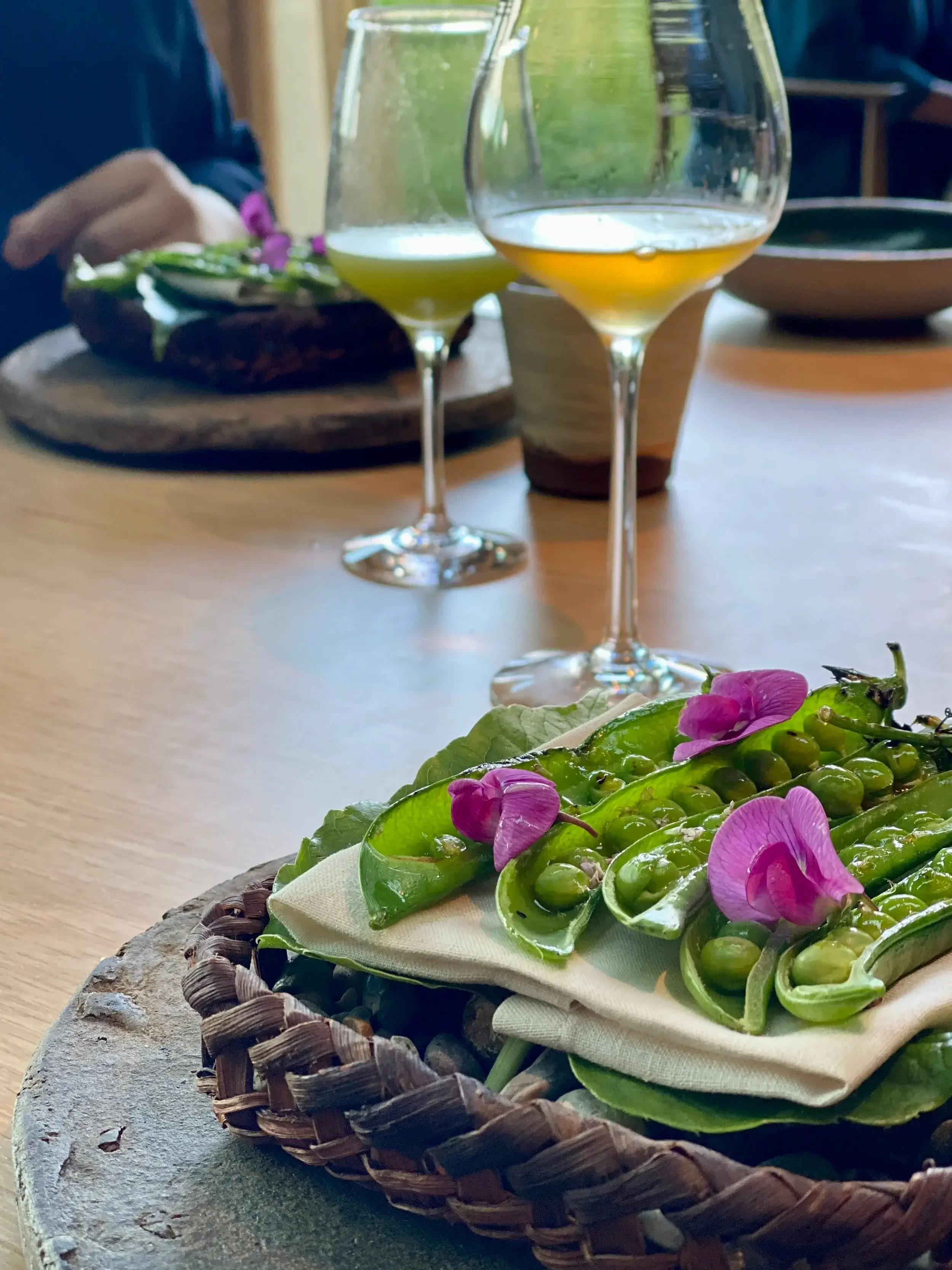 A plate of green beans accompanied by a glass of red wine on a wooden table.