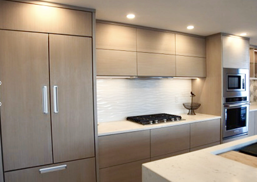 Modern kitchen with light wood cabinets, built-in stainless steel oven and microwave, stove, and white countertops.