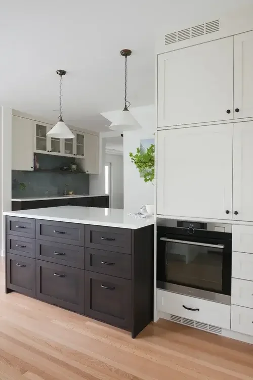 A modern kitchen featuring white cabinets and warm wood floors, creating a bright and inviting atmosphere.
