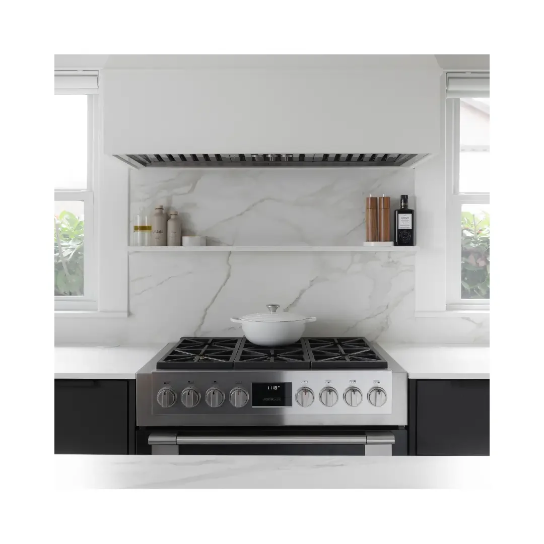 A stainless steel stove top oven sits on a white marble countertop, showcasing a modern kitchen design.