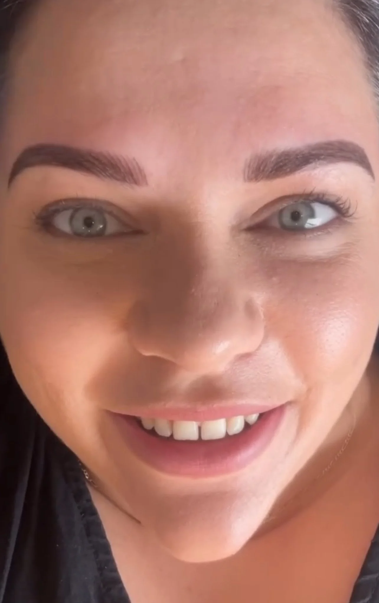 Close-up of a smiling woman with bright eyes, well-groomed eyebrows, and smooth skin.