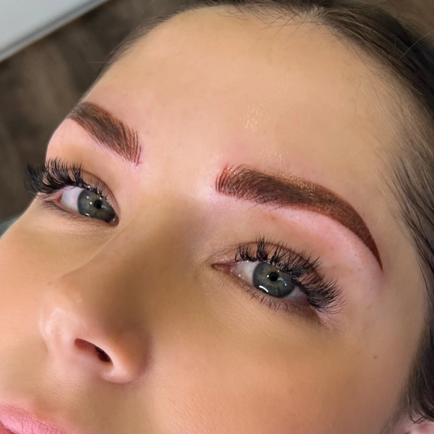Close-up of a woman with makeup, focusing on her eyebrows, eyes with false lashes, and smooth skin.