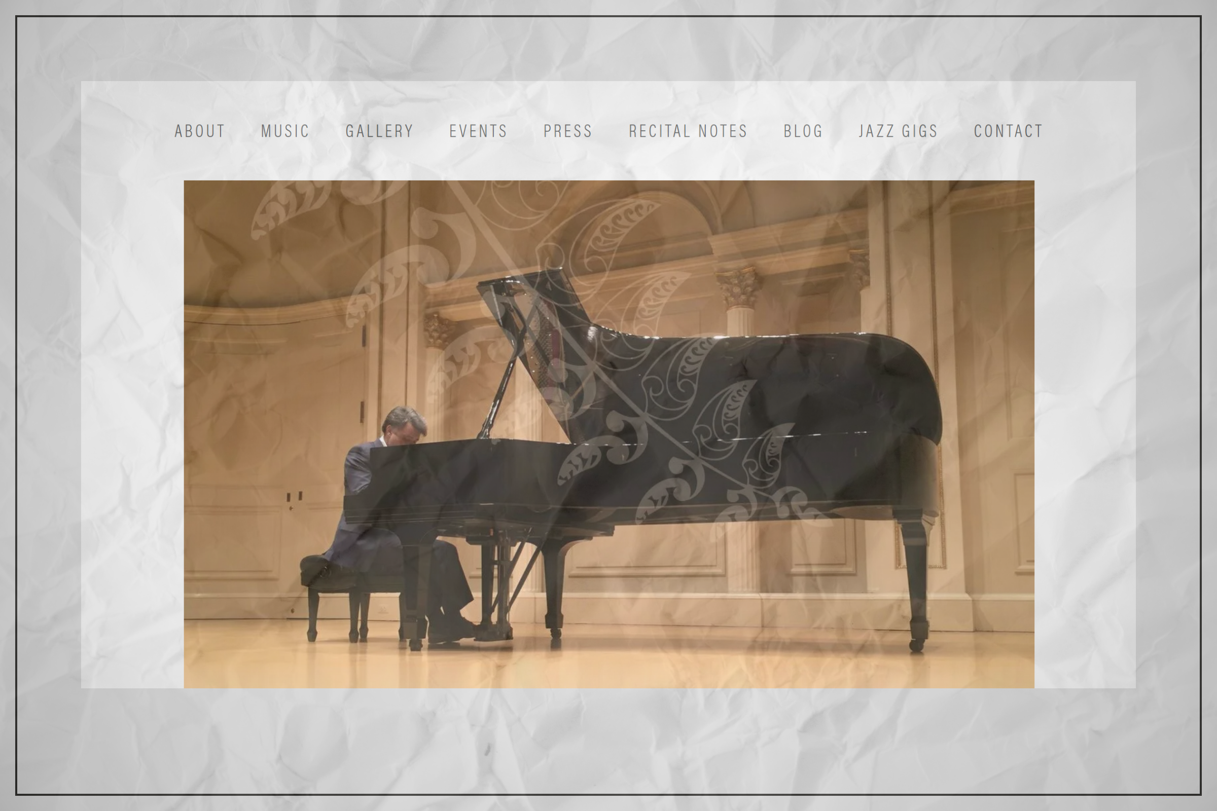 A man playing a grand piano on a stage inside a decorated concert hall.