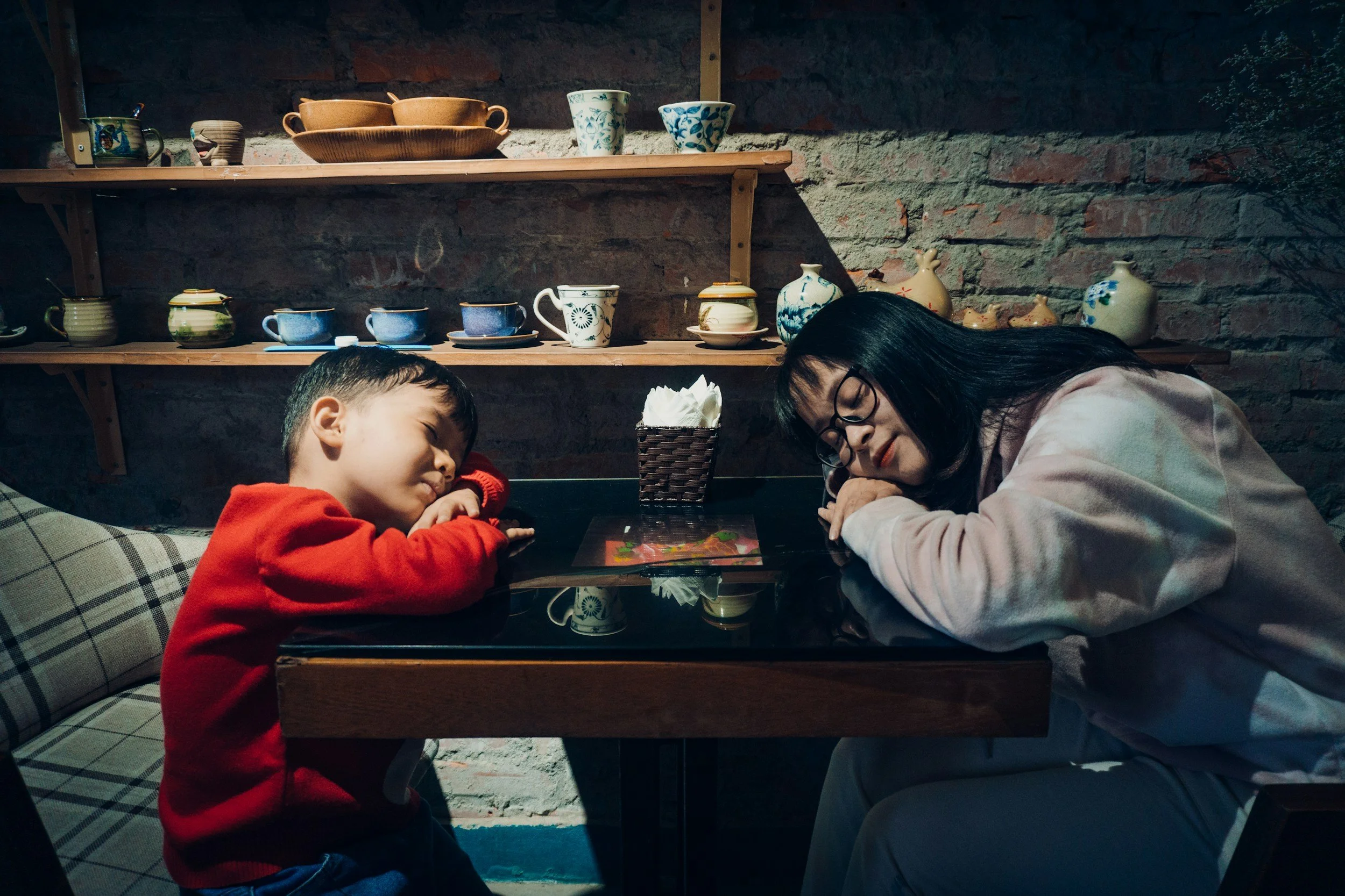 A mother and her child with their head on a table resting briefly