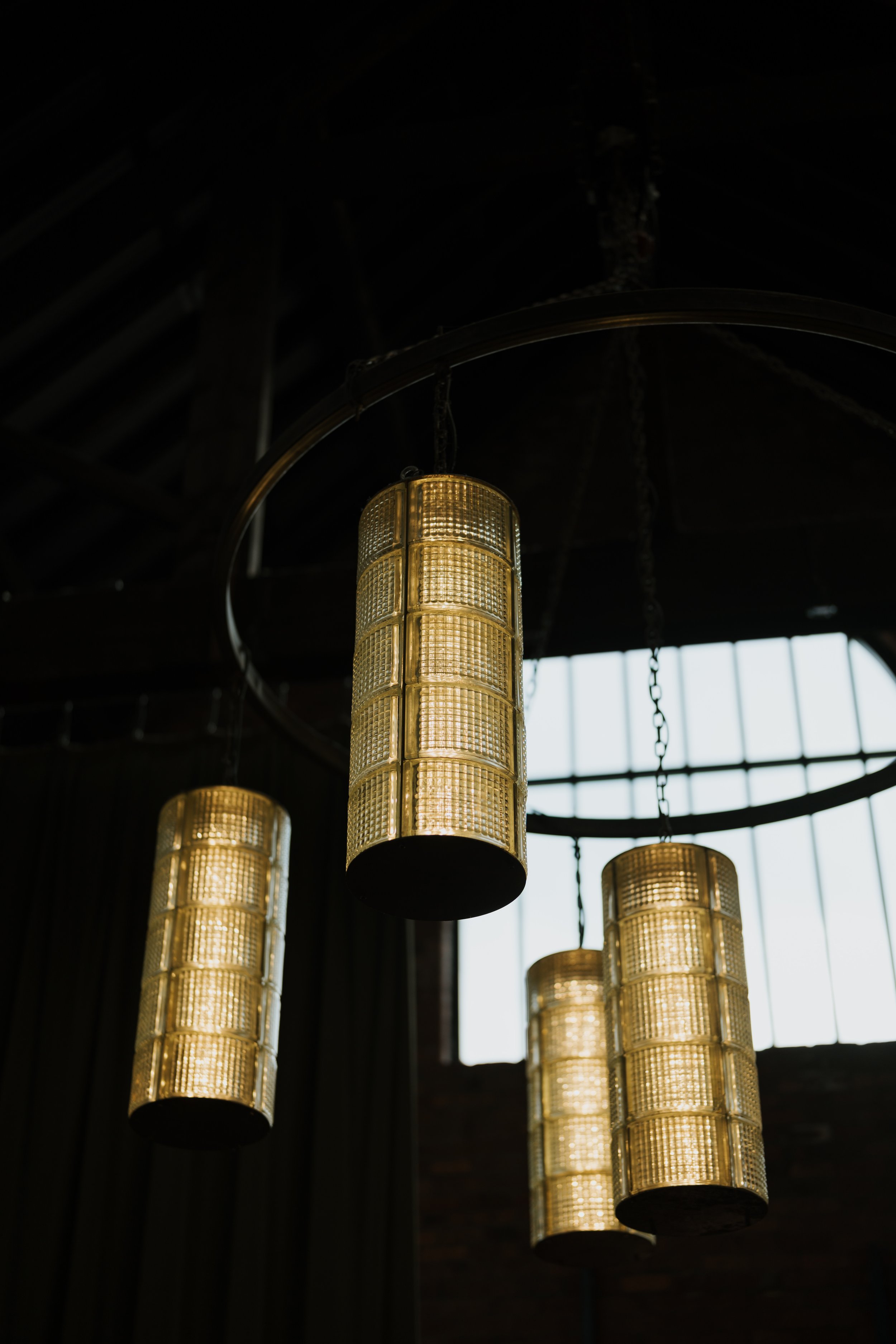 Hanging cylindrical glass pendant lights in a dimly lit interior with a large window background.