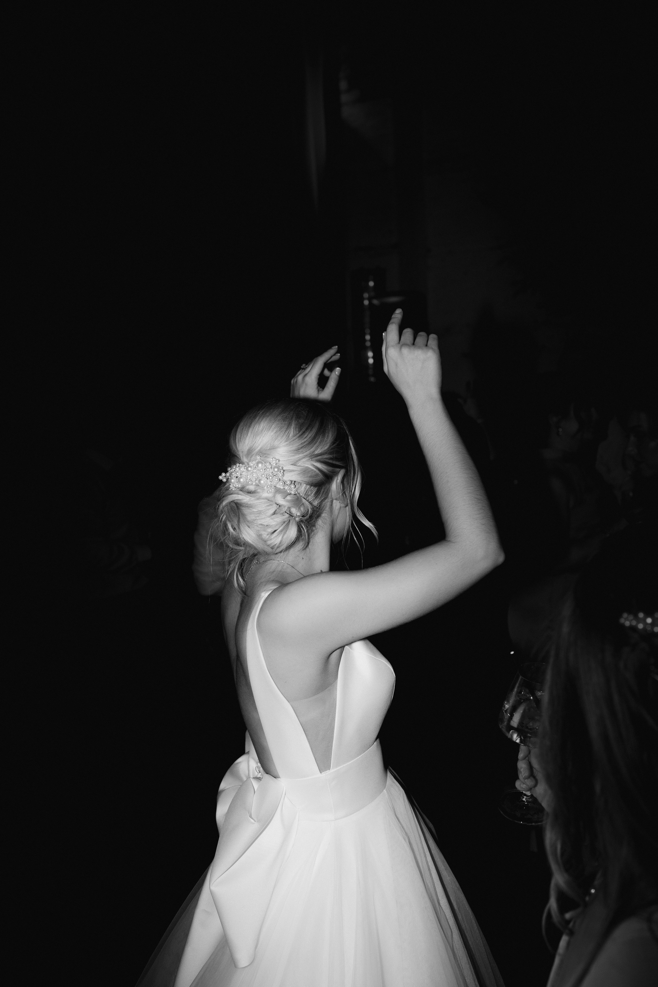 Bride dancing in white dress at a wedding reception, black and white photo.