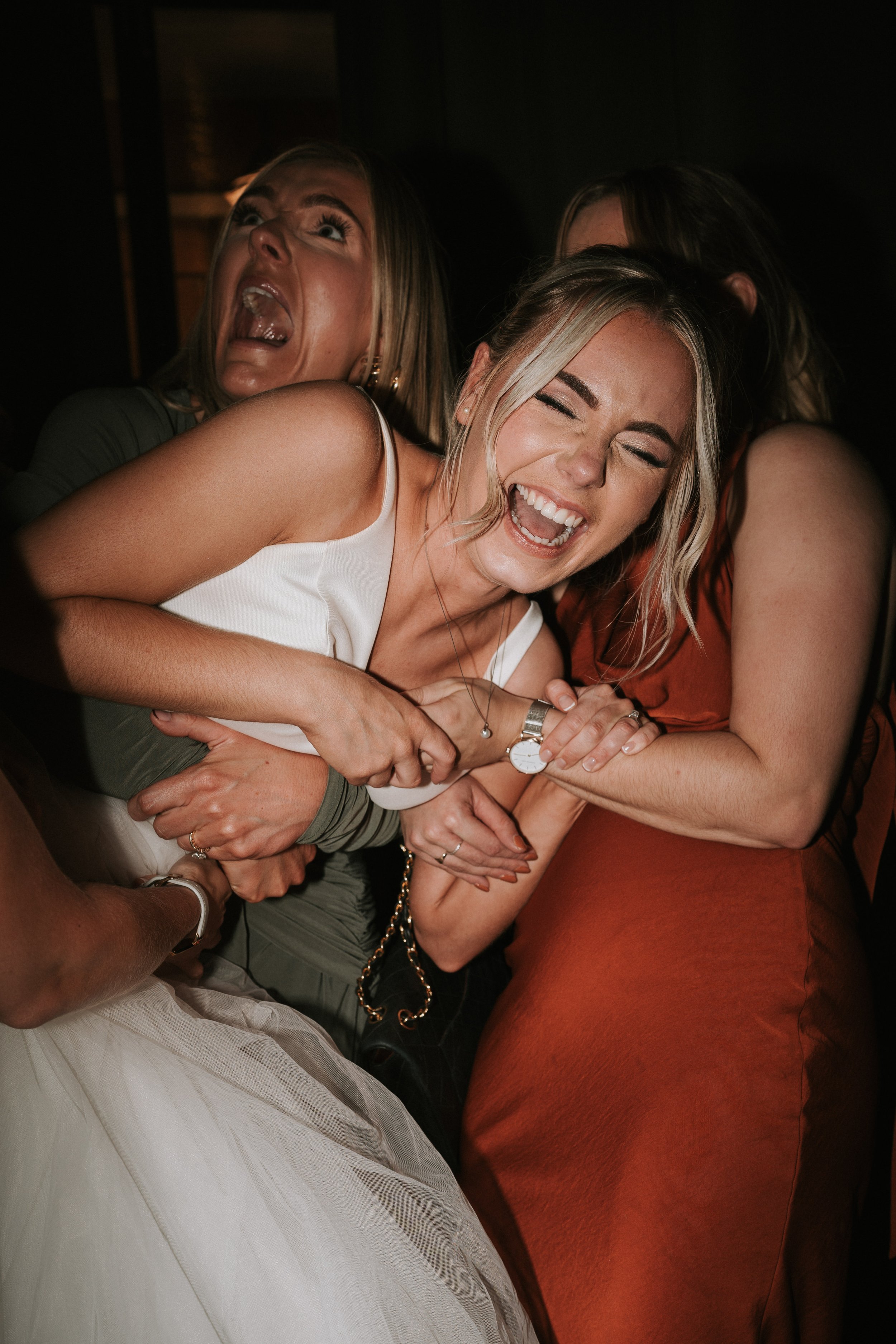 Group of women having fun at a party, laughing and hugging.