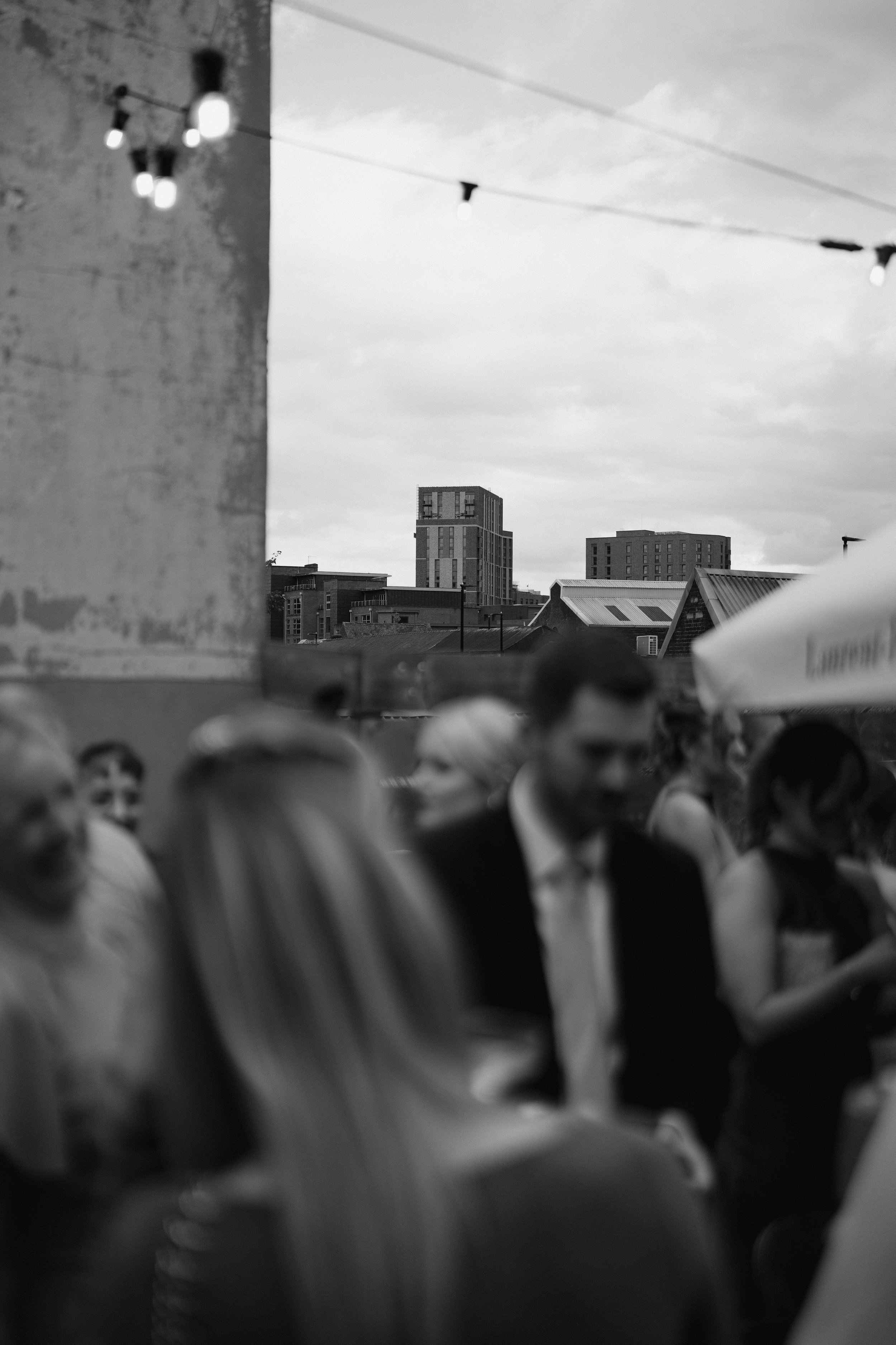 black and white photo of people at an outdoor gathering with urban buildings in the background