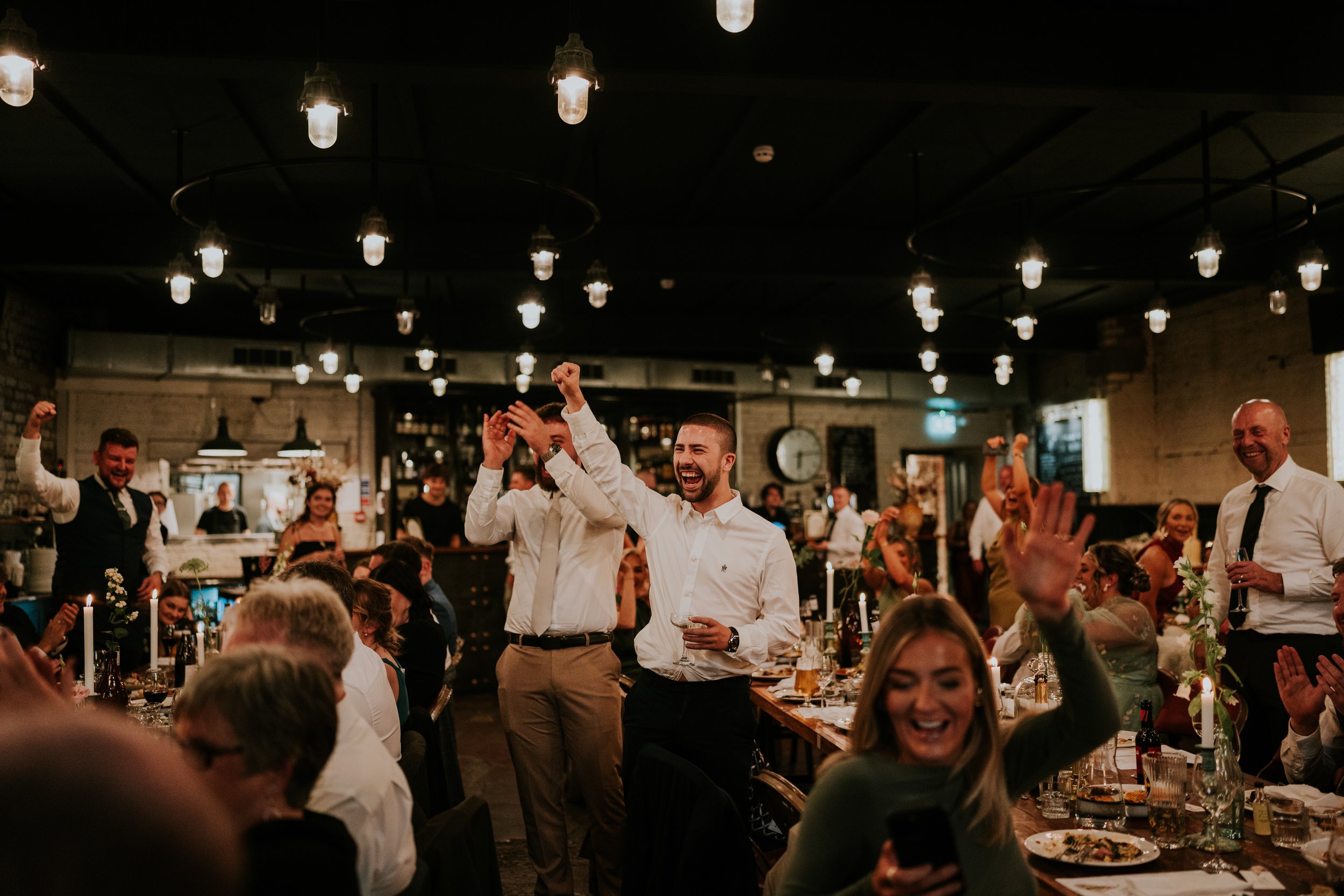 People celebrating at an indoor event with festive lighting.