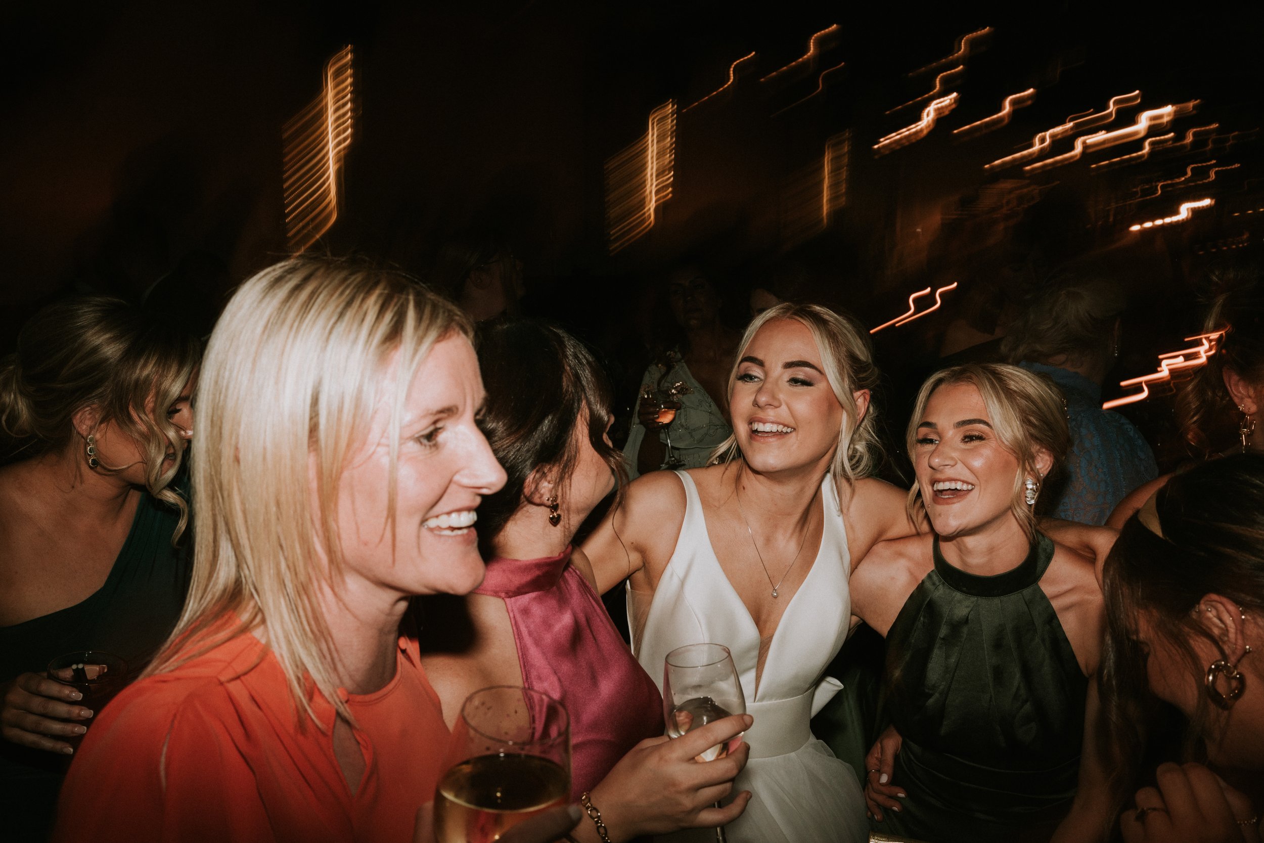 Group of women smiling and holding drinks at a party.