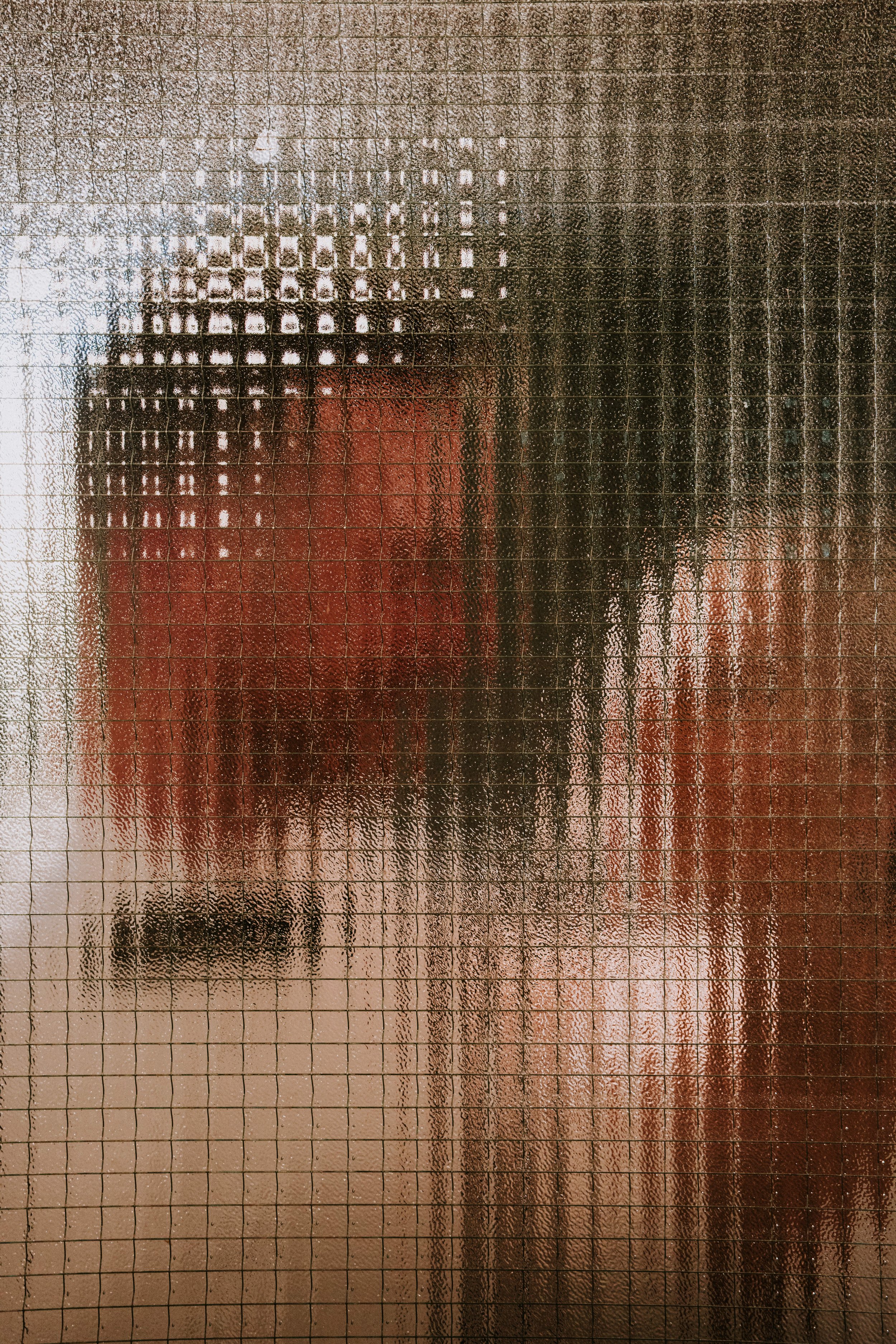 Blurry red and brown shapes behind textured glass