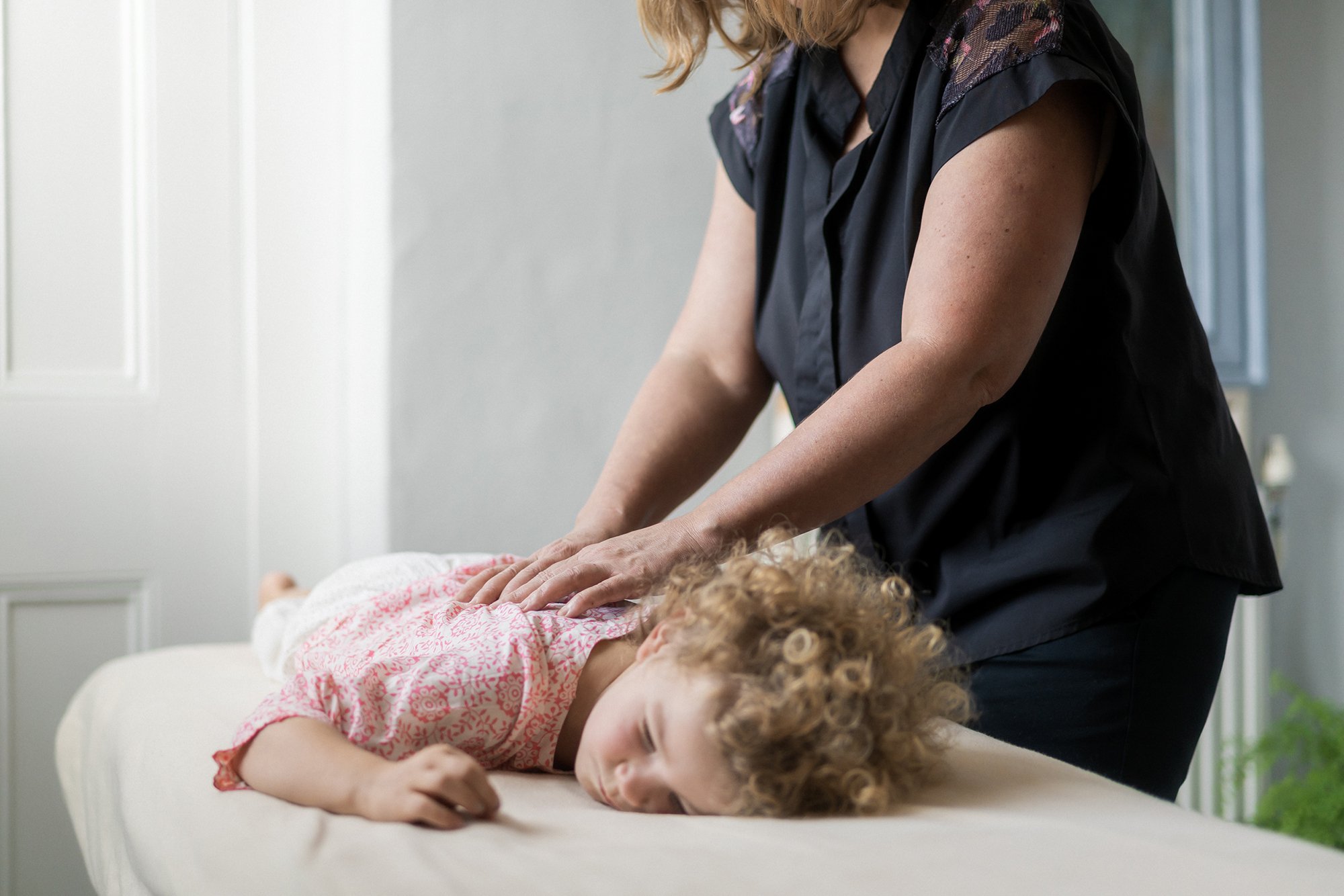 Toddler lying on front receiving back treatment
