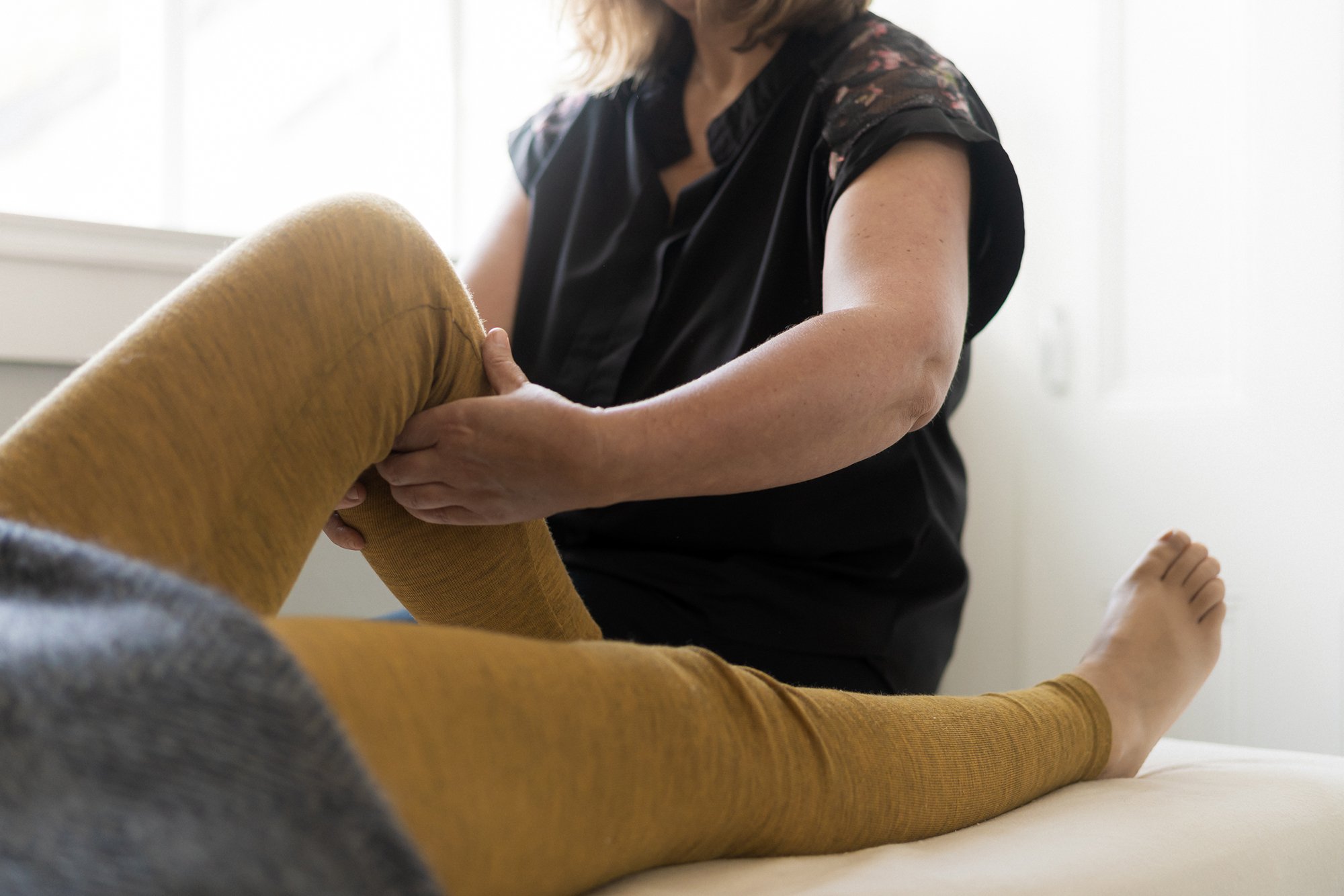 Woman lying on back receiving knee treatment