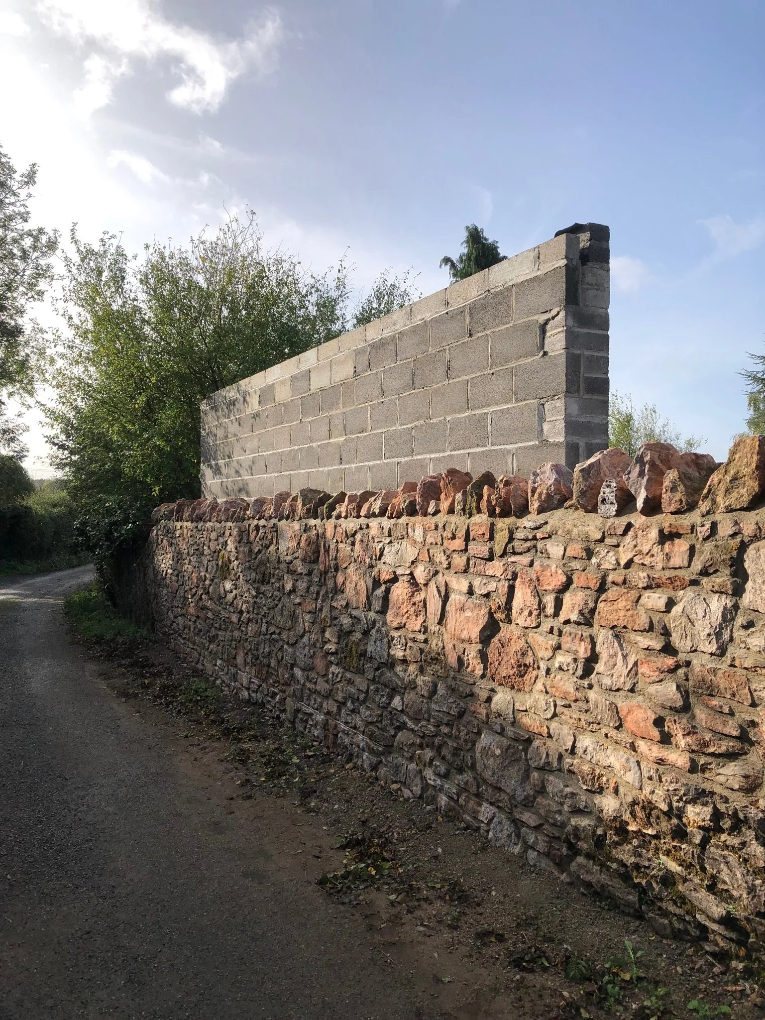 The stone wall seamlessly rebuilt and a new block wall built behind it