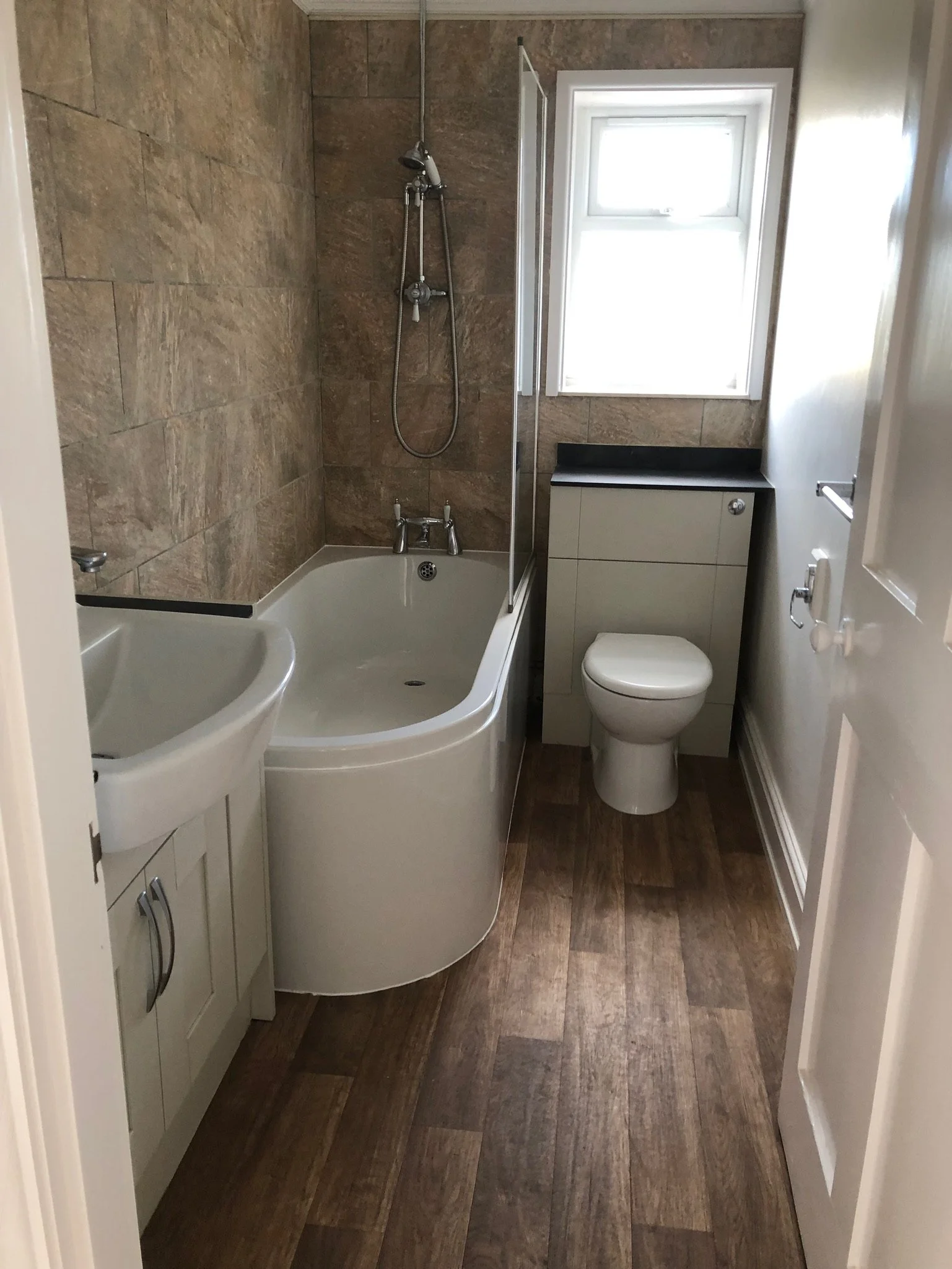 A newly installed bathroom with sink, toilet and bath with shower above
