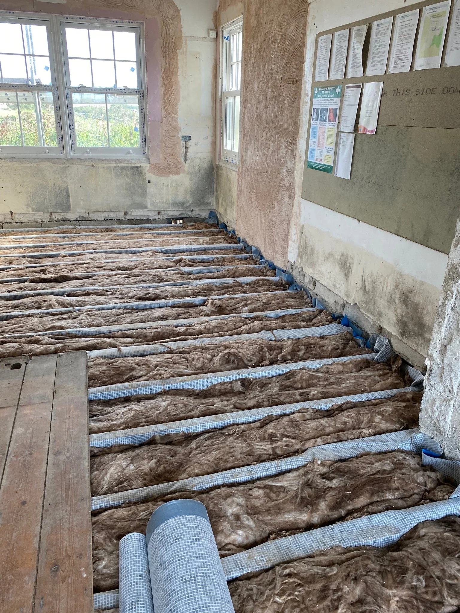 The underfloor insulation laid between floor joists, awaiting the next layer.