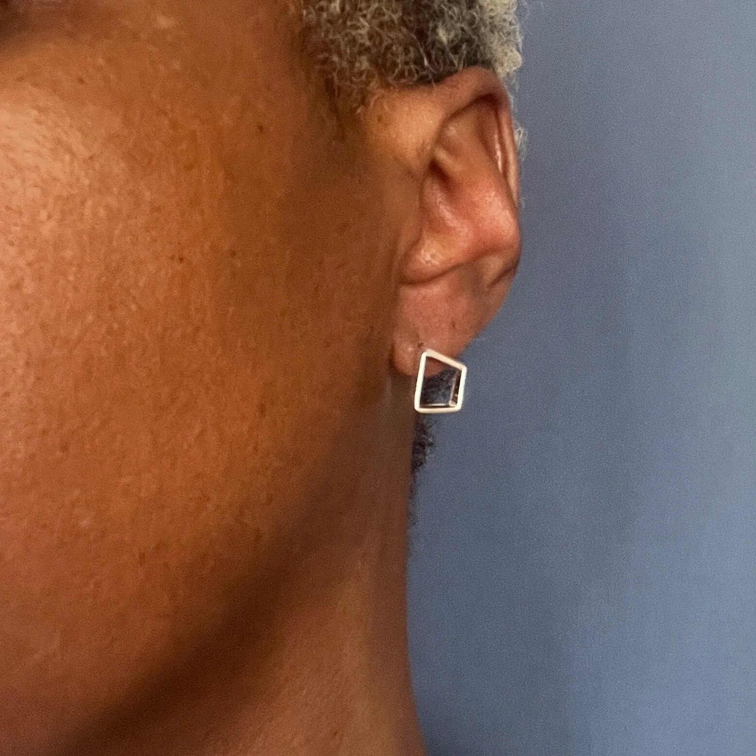 Small geometric silver earrings on model