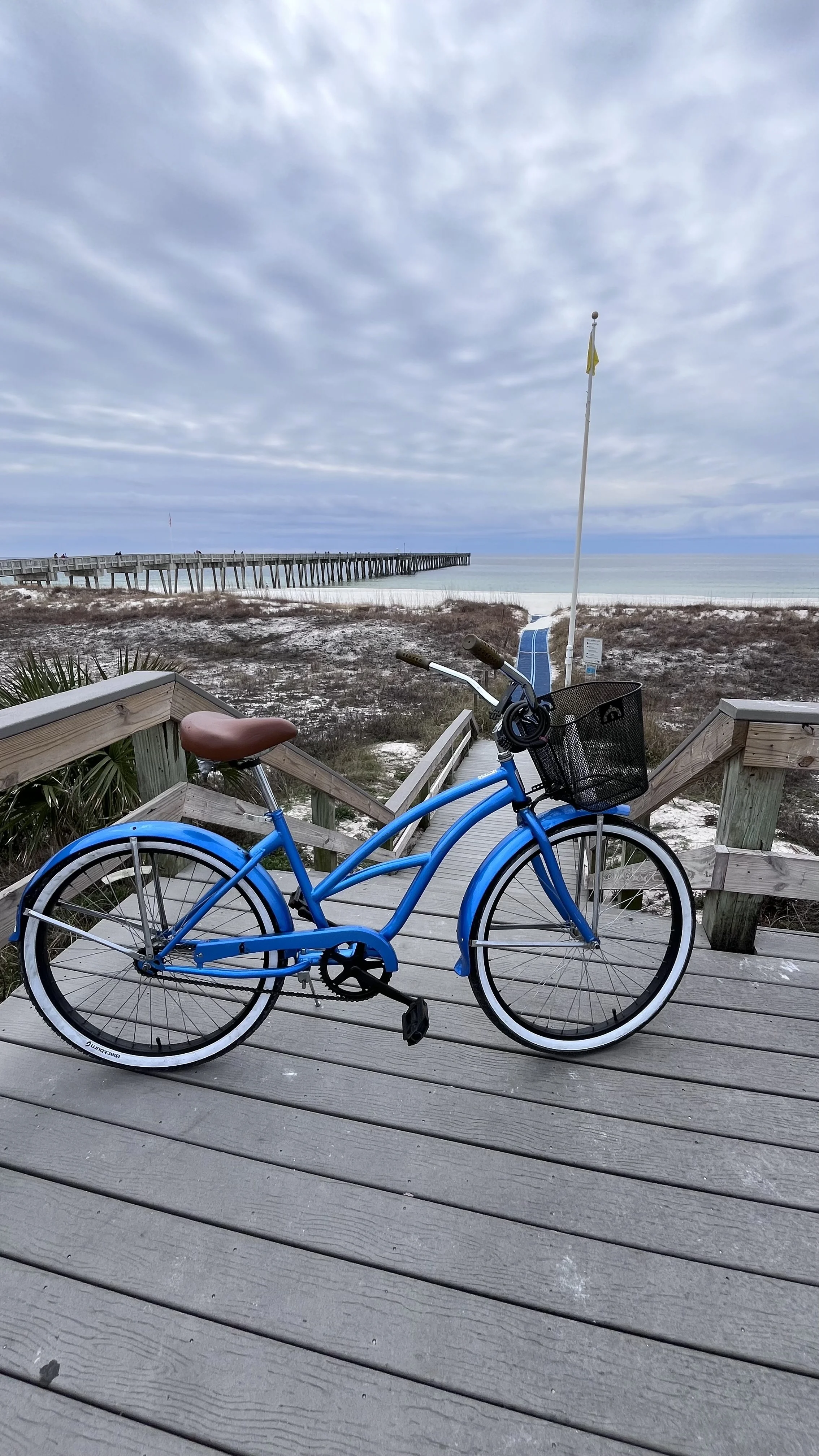 Blue rental bike on a boardwalk by the beach and pier in Panama City Beach, Florida.