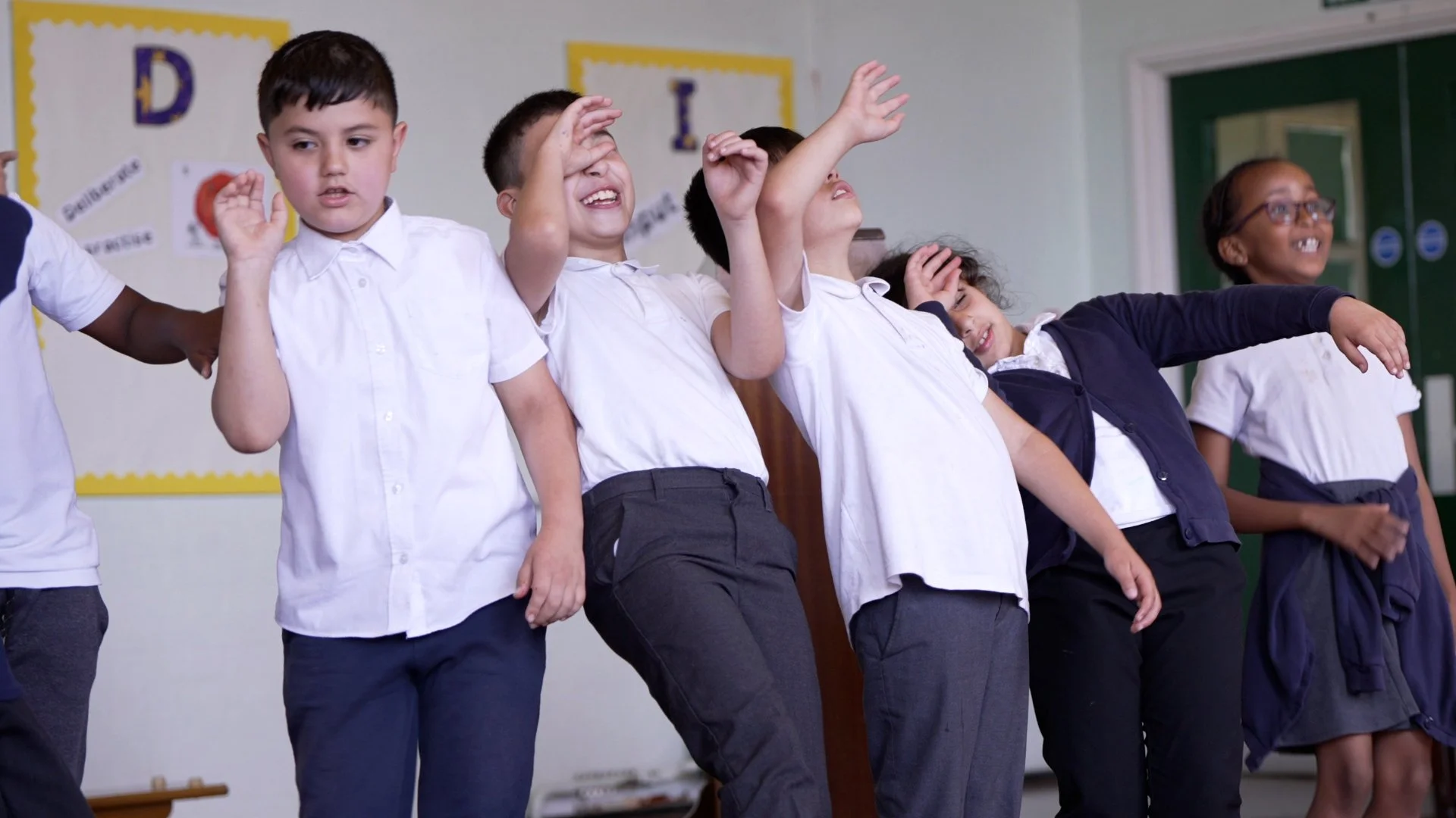 Group of young children in school uniforms performing a dance or play on stage