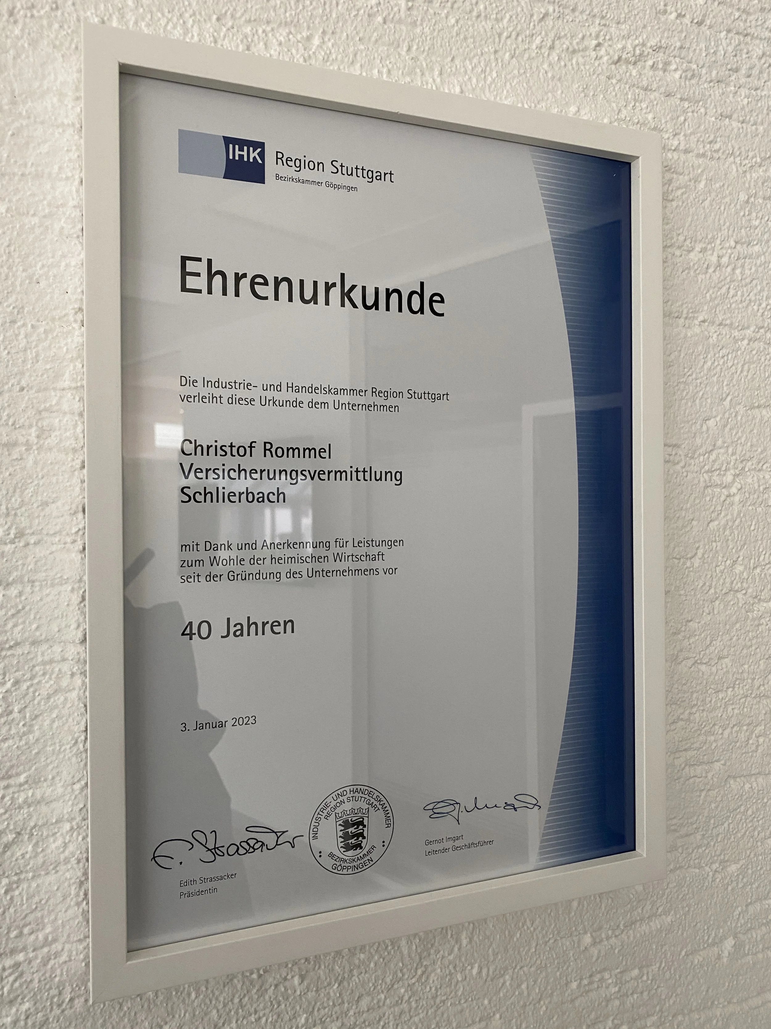 Rahmen mit einer Ehrenurkunde der IHK Region Stuttgart, ausgestellt am 3. Januar 2023. Sie ehrt ein Unternehmen für Leistungen zum Wohl der heimischen Wirtschaft über 40 Jahre. Handschriftliche Unterschriften und das Logo der IHK sind sichtbar.