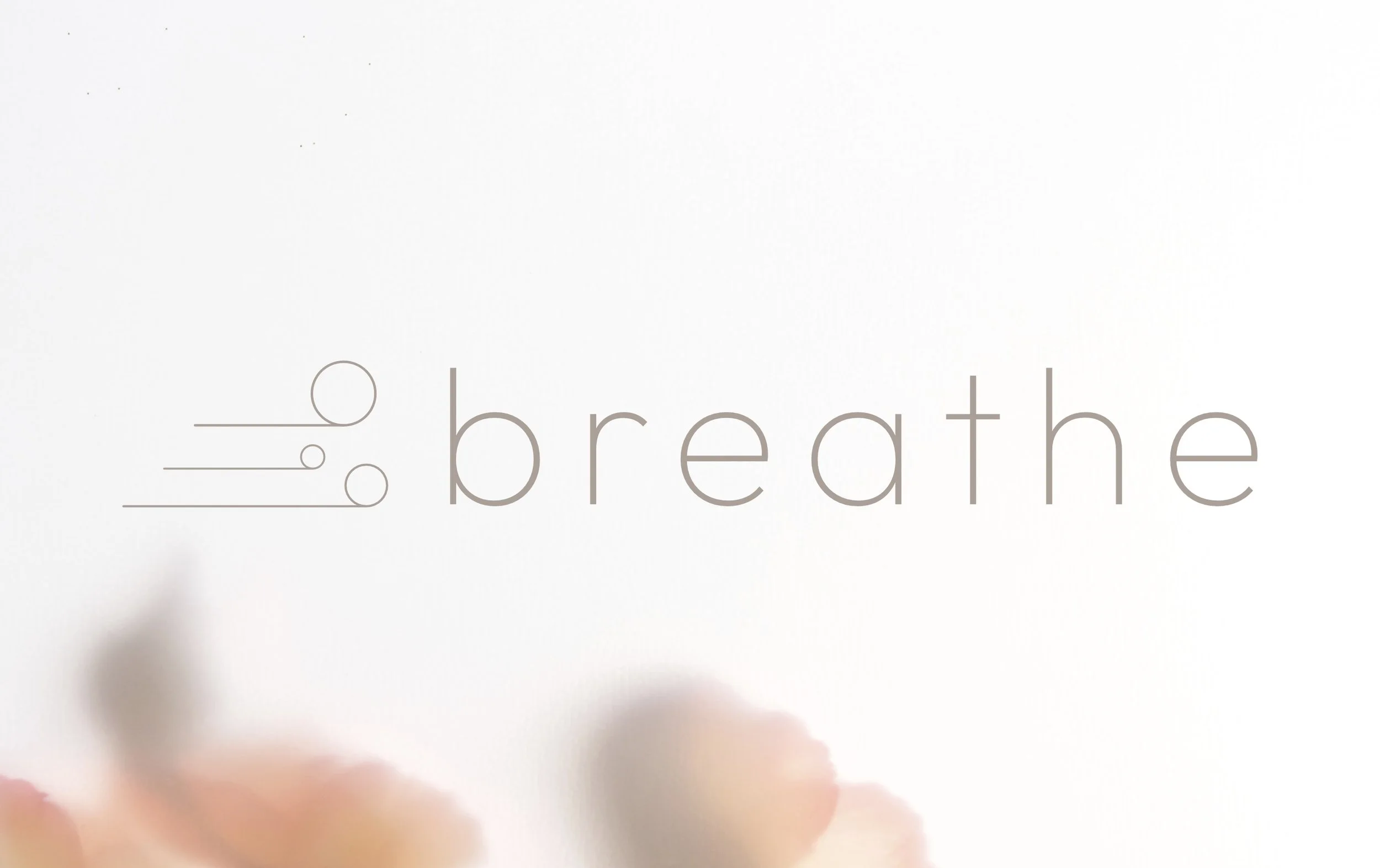 Close-up of a white card with the word 'breathe' written in light gray, lowercase letters, and decorative lines and circles.