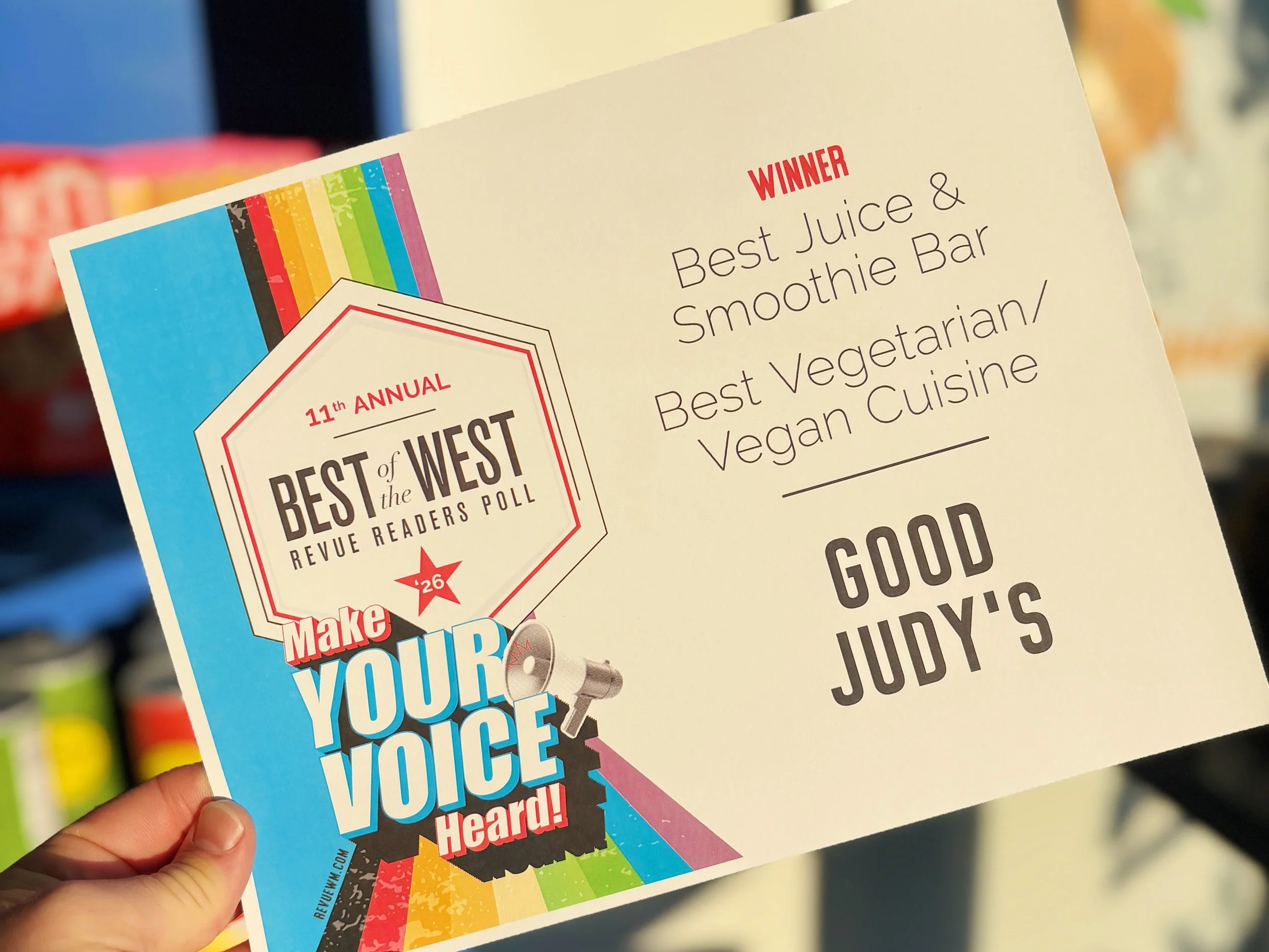 Dean holding an award from Revue Magazine naming them the best juice bar and best vegetarian/vegan cuisine in West Michigan