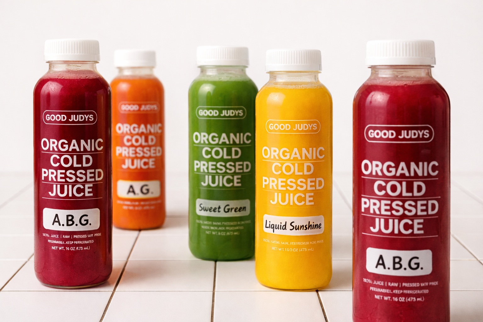 Six cold-pressed juices from a juice cleanse on a white table