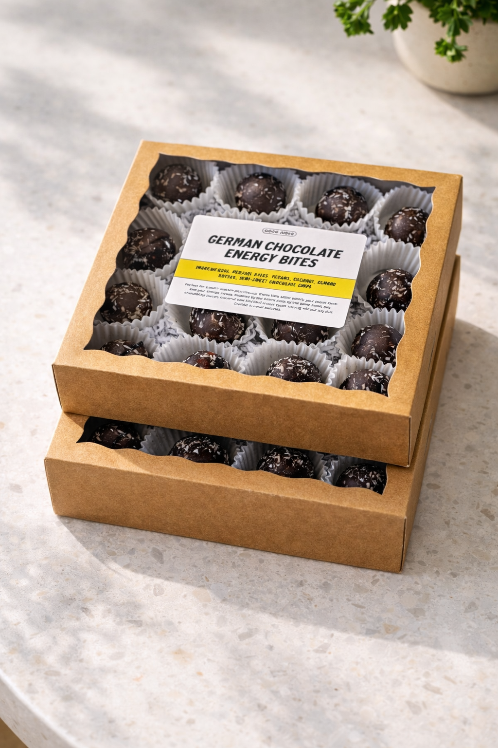 Box of German chocolate energy bites with dark chocolate coating and sprinkled with sea salt, displayed on a light-colored surface.
