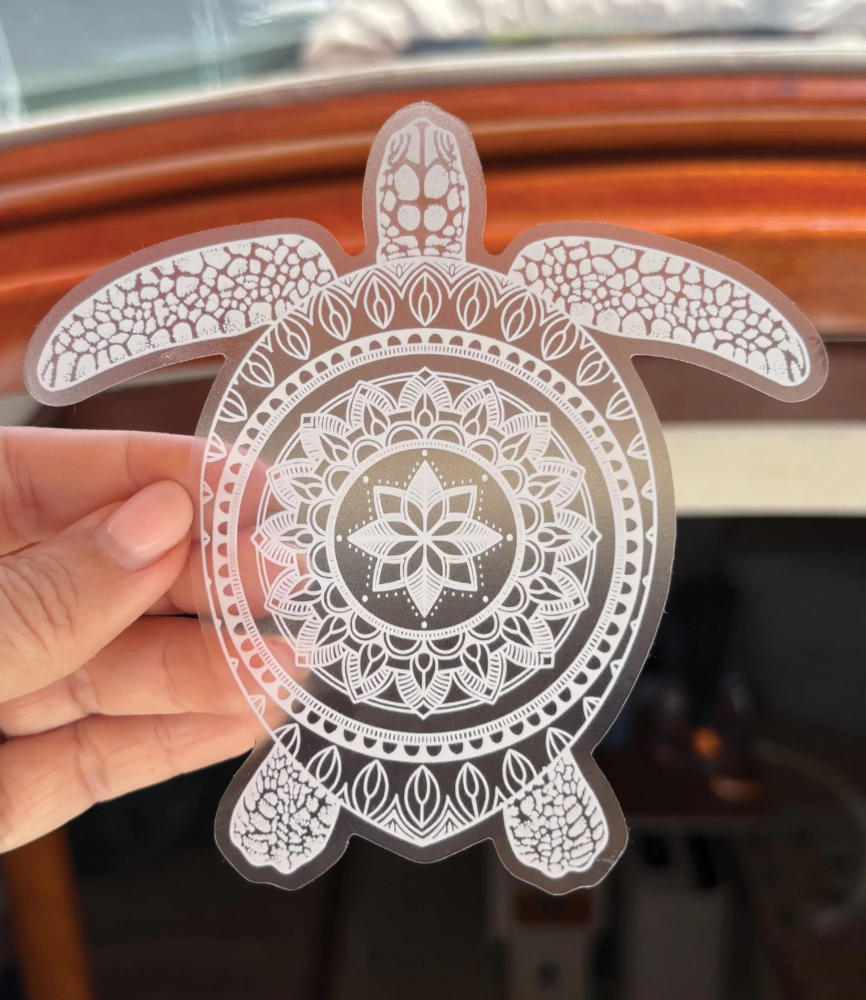 Vinyl sticker with a clear background featuring a drawing of a turtle with a mandala pattern on its shell. Unique ocean art encapsulated into a durable, waterproof sticker.