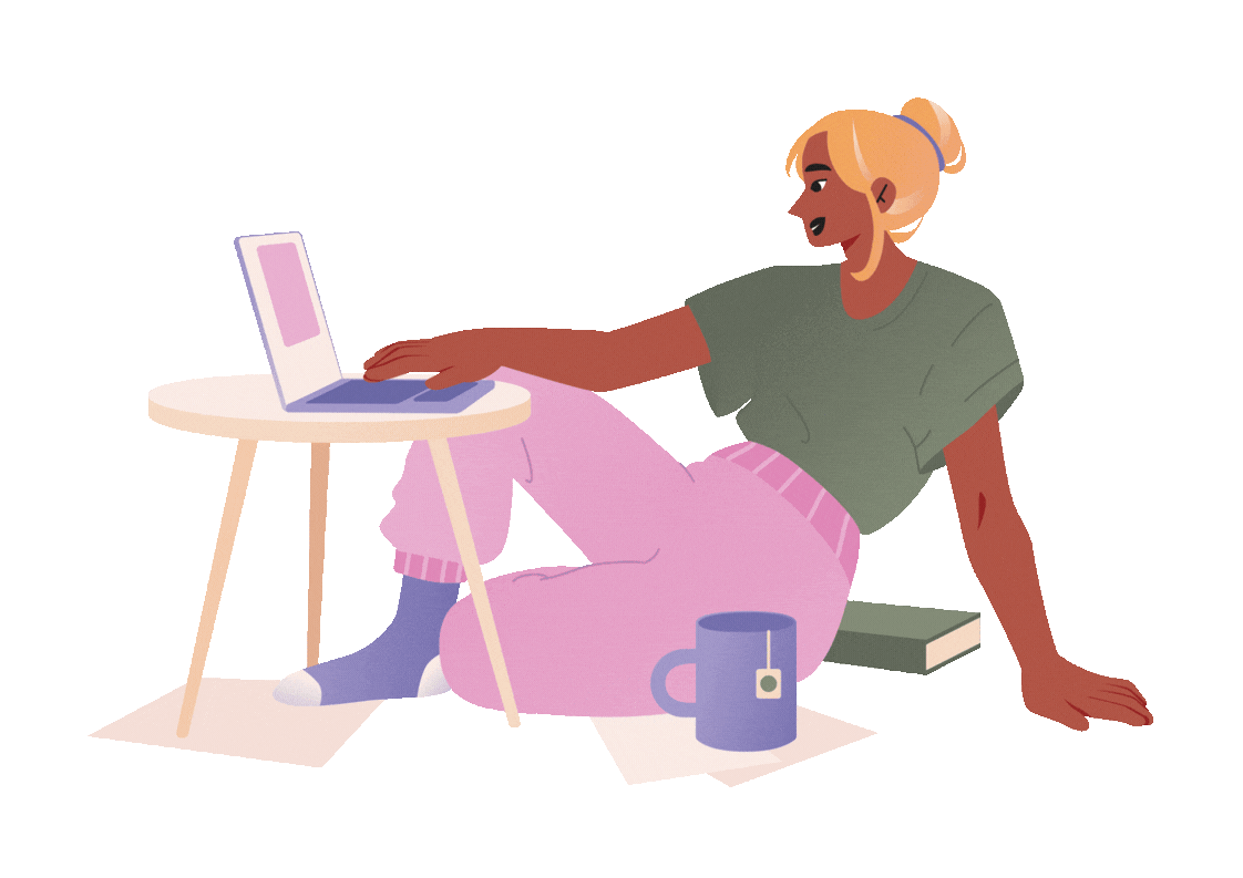 A young woman with blonde hair sitting cross-legged on the floor, working on a laptop placed on a small round table, with a mug and a book nearby.