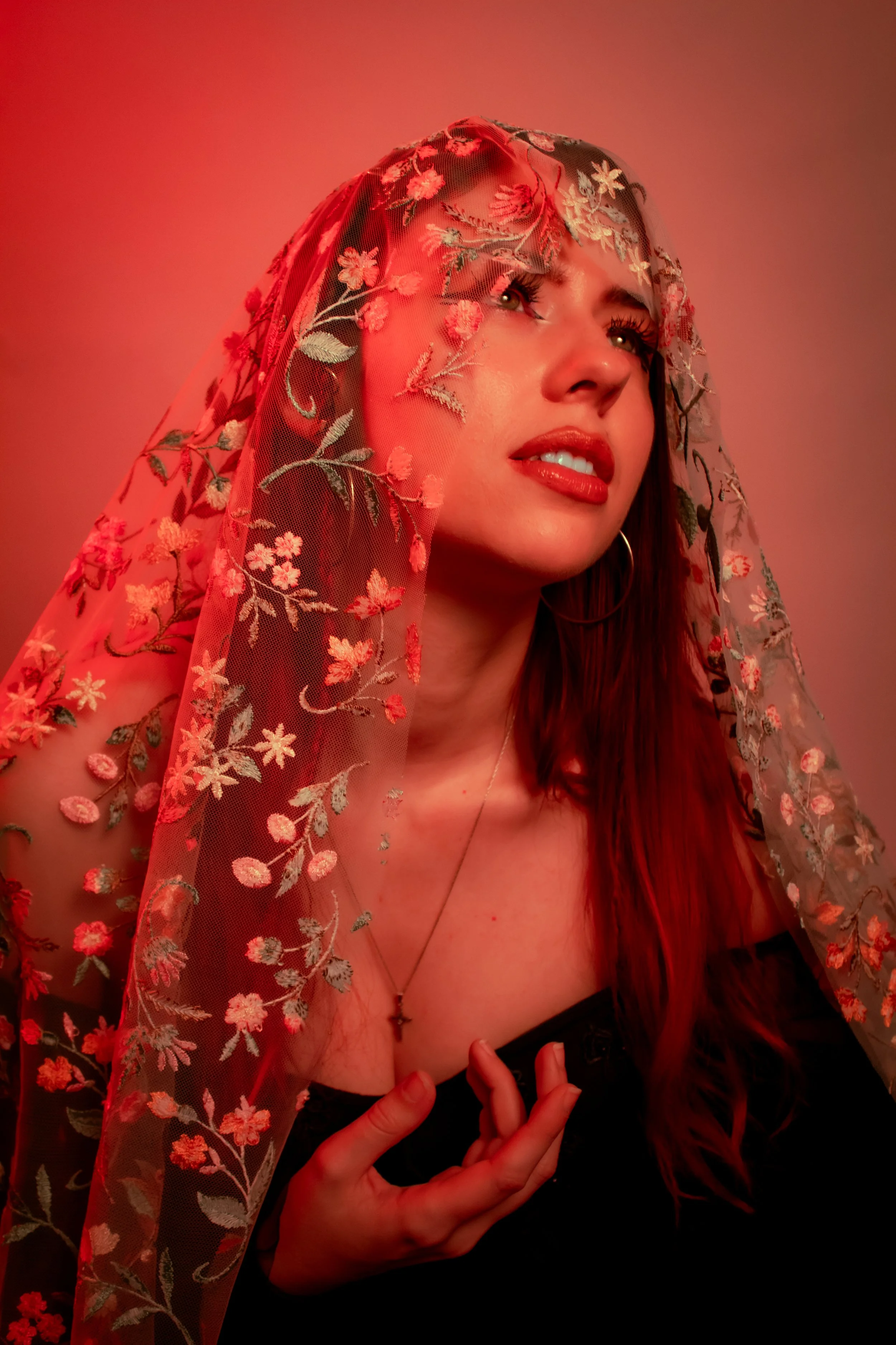 Fine art portrait photography featuring dramatic red lighting, floral textures, and creative conceptual styling.