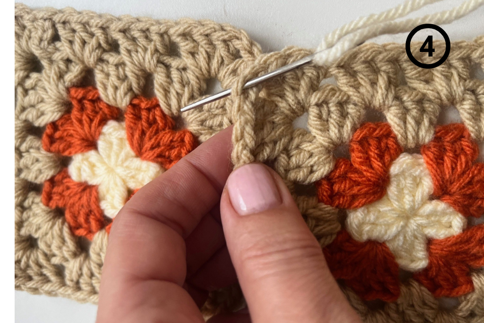 Yarn needle inserted through the edge stitches of both squares.