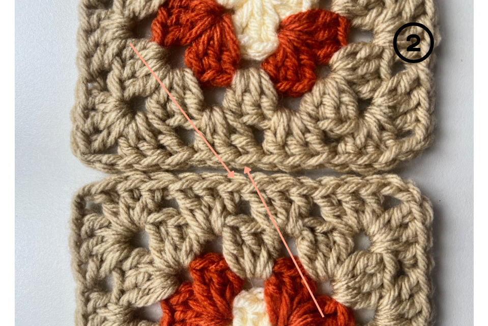 Yarn needle inserted through the edge stitches of both squares.
