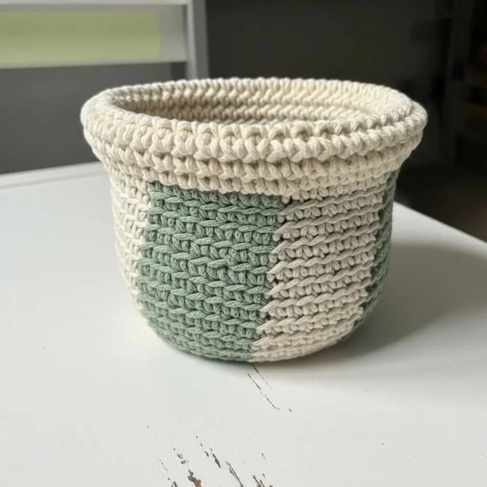Handmade crochet basket in cream and sage green with a folded rim