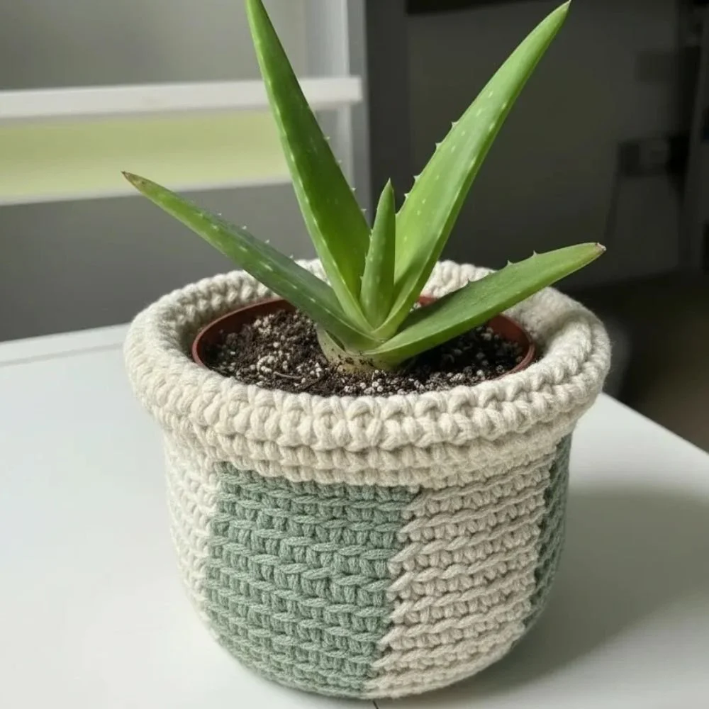 Small round crochet storage basket made with chunky cotton yarn in neutral cream and grey tones.