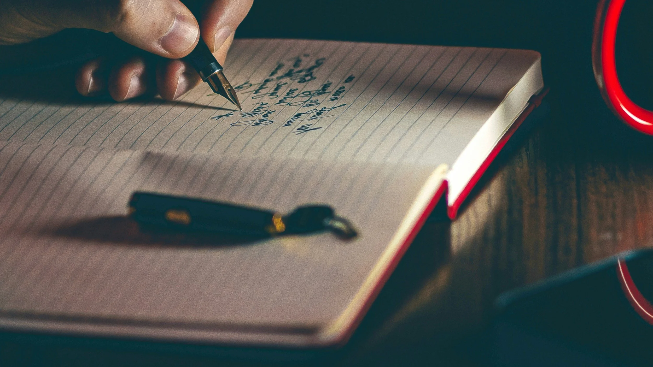 Fiction excerpt being edited in red notebook with ink pen