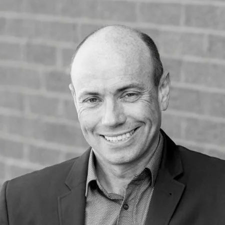 Smiling person in a suit with a brick wall background