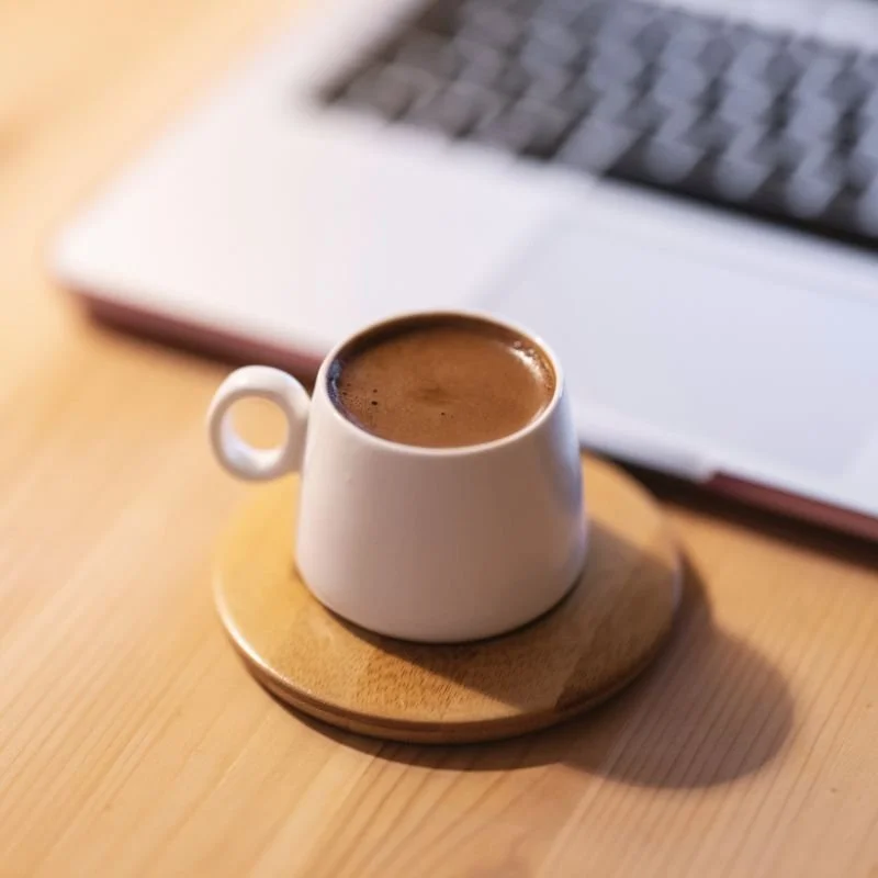 Cup of coffee beside a laptop, representing therapy for imposter syndrome in high-achieving women in Philadelphia