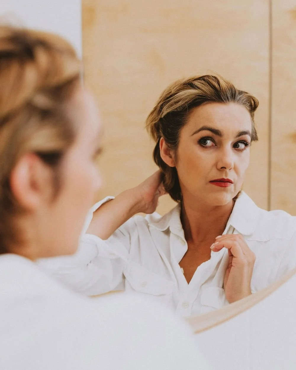 Woman studying her reflection in a mirror, representing the self-scrutiny addressed in perfectionism therapy