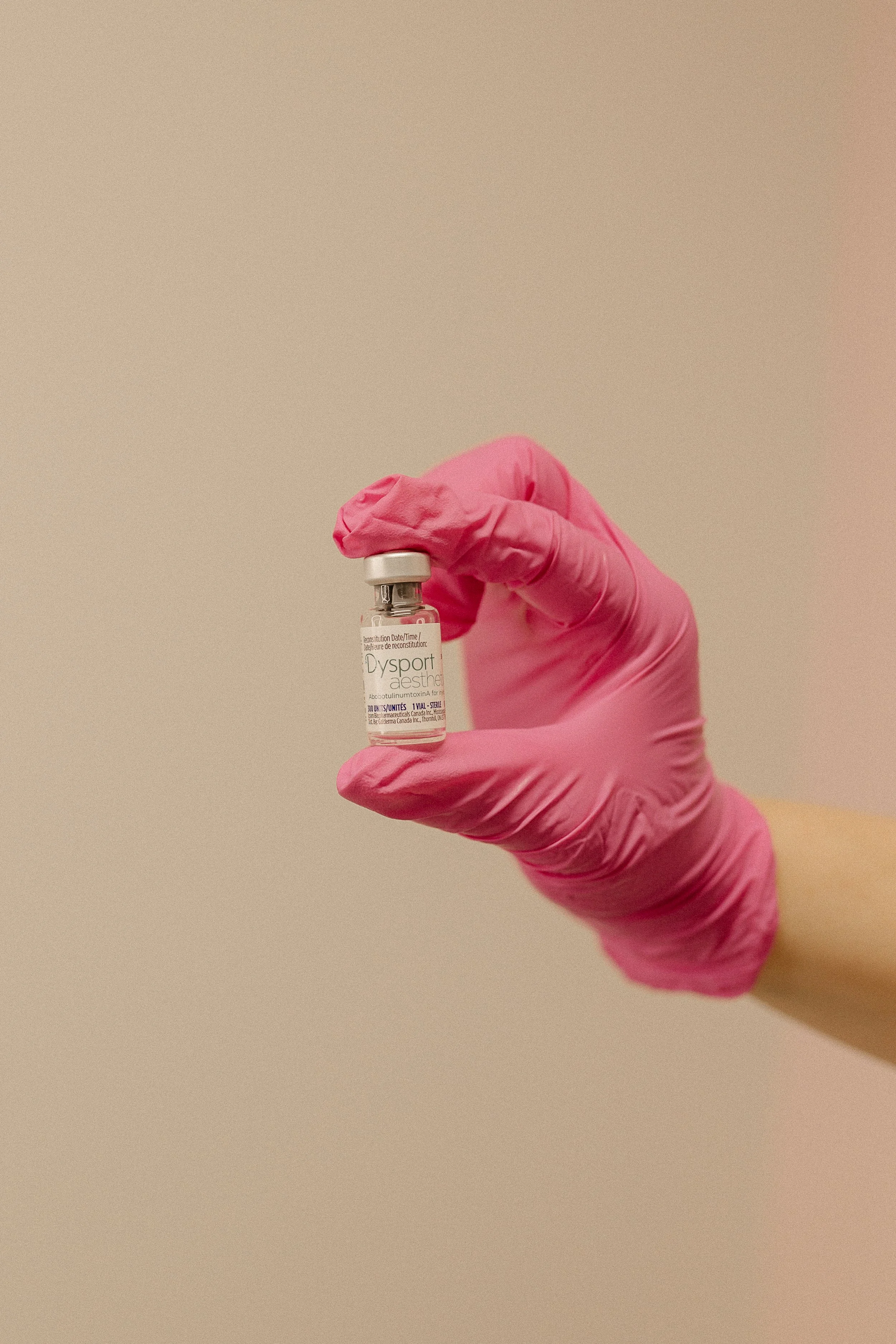 Person holding two syringes with orange caps in focus, background blurred.