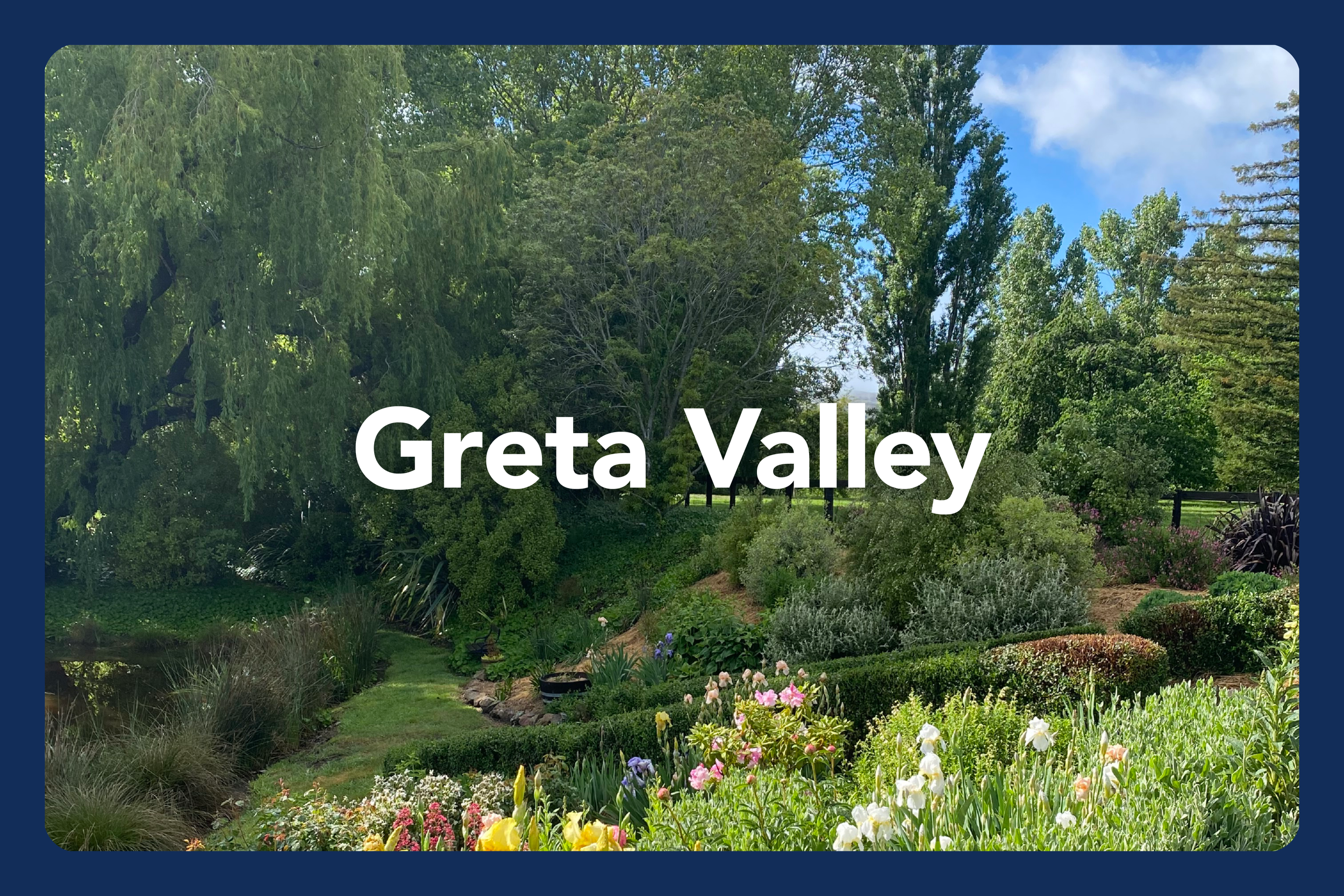 Landscape view of Greta Valley with lush green trees, bushes, flowers, and a small pond under a partly cloudy sky.