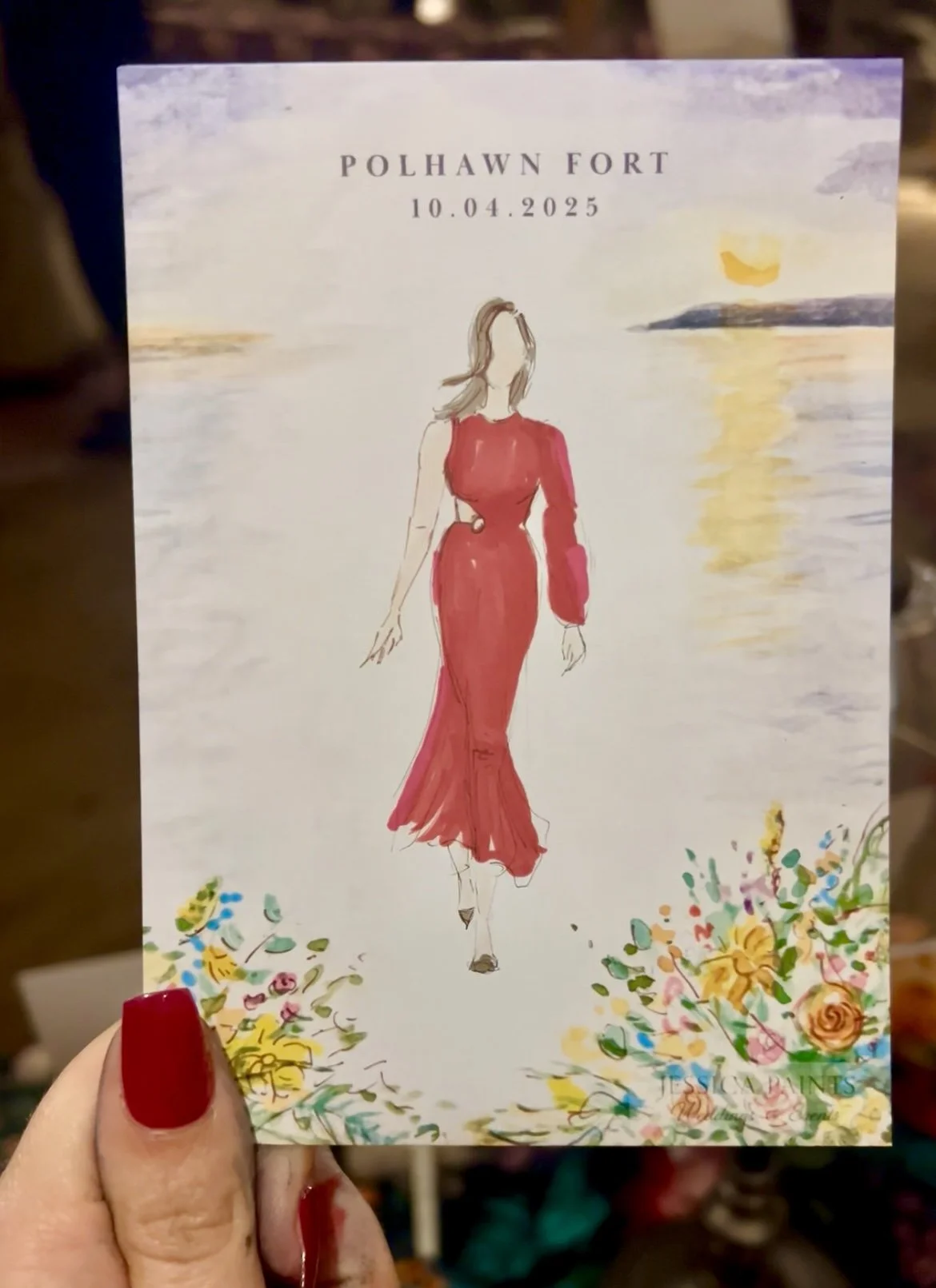 live painter holding watercoloring guest painting with handprinted border design in Cornwall