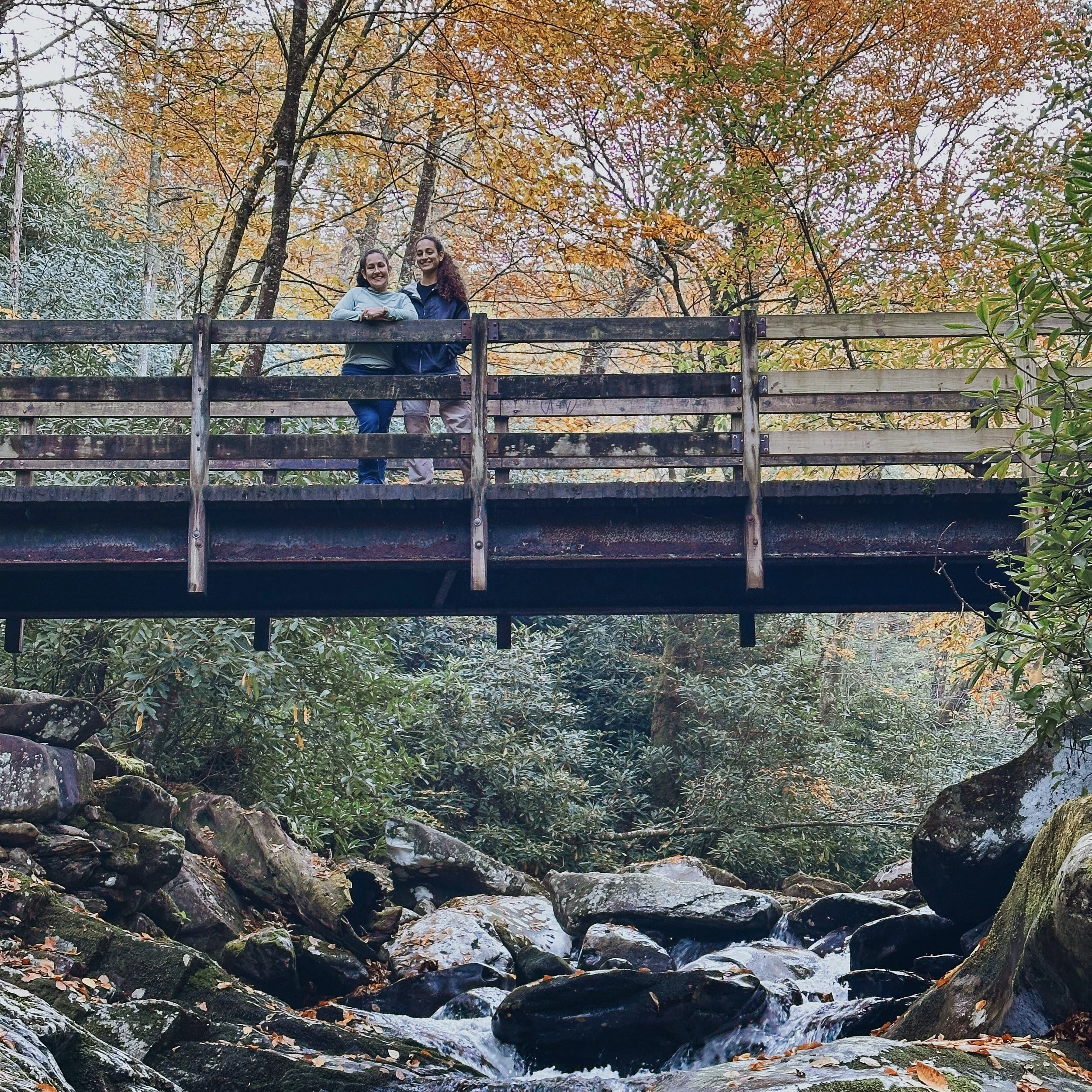 Mother and daughter on a bridge over a creek in Great Smoky Mountains National Park in fall